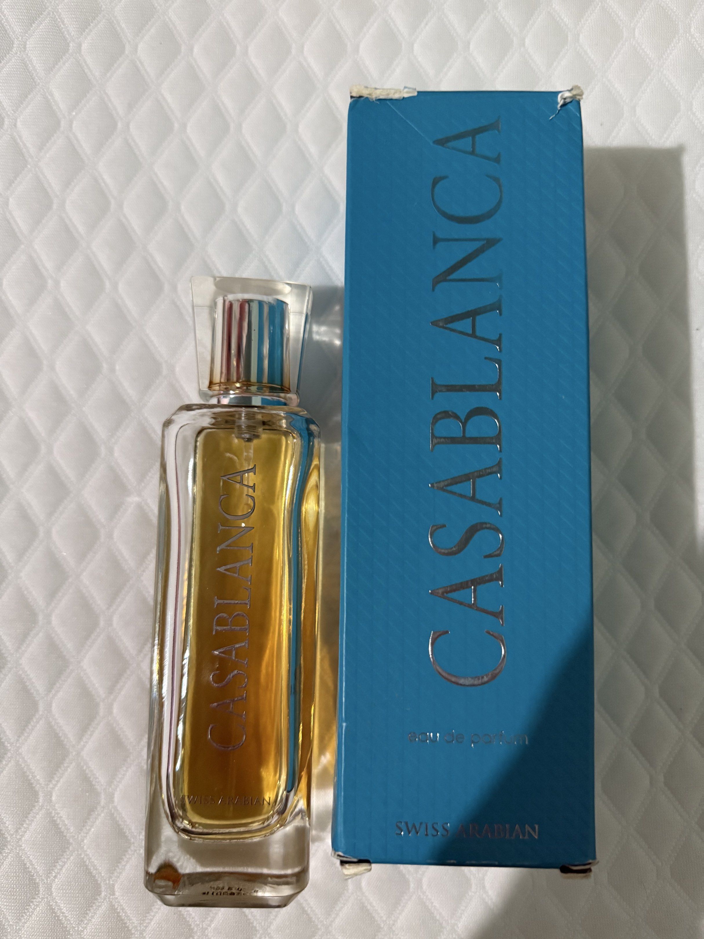 Swiss Arabian Casablanca Eau de Parfum (Category: Fragrance & Deodorants) located in Tarlac. Submitted by yoona88 (Listing ID 1417035948, Image 2). Description: - Swiss Arabian Casablanca Eau de Parfum - Includes original blue box with silver lettering - Rectangular perfume bottle with clear cap - Golden-colored perfume liquid - Brand name printed on the bottle - Half full.