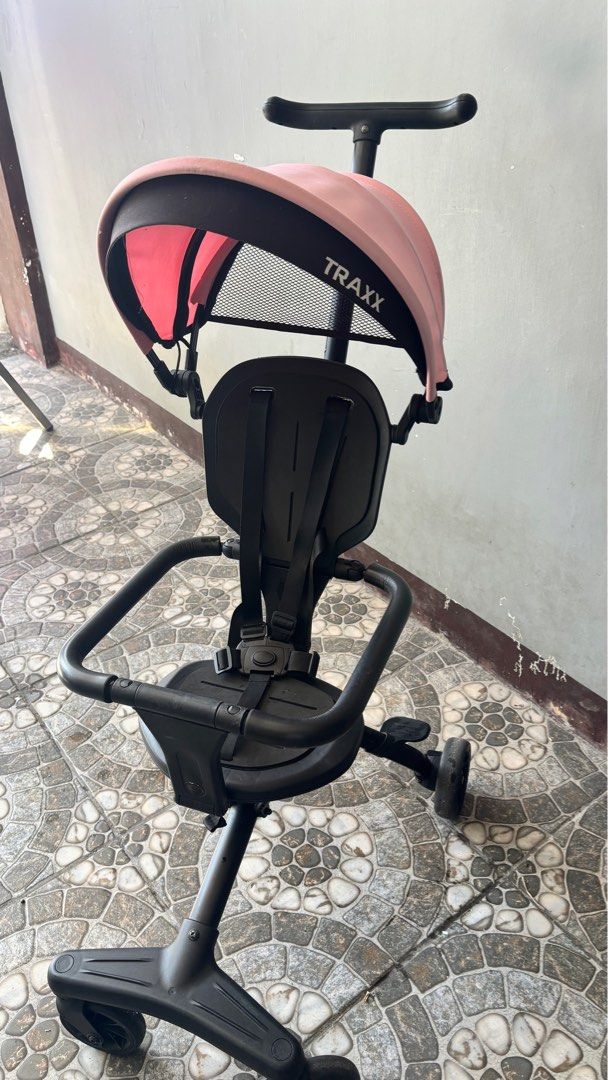 Foldable Traxx Baby Stroller Tricycle (Category: Strollers) located in San Jose. Submitted by arakyer (Listing ID 1417054868, Image 2). Description: - Traxx baby stroller tricycle - Pink canopy, black frame - Safety seat with straps - Steering handle for parent control - Three-wheel design - Includes footrests - Foldable for easy storage - Traxx logo present.