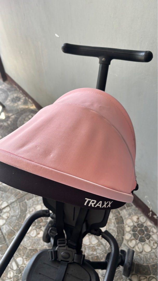 Foldable Traxx Baby Stroller Tricycle (Category: Strollers) located in San Jose. Submitted by arakyer (Listing ID 1417054868, Image 3). Description: - Traxx baby stroller tricycle - Pink canopy, black frame - Safety seat with straps - Steering handle for parent control - Three-wheel design - Includes footrests - Foldable for easy storage - Traxx logo present.