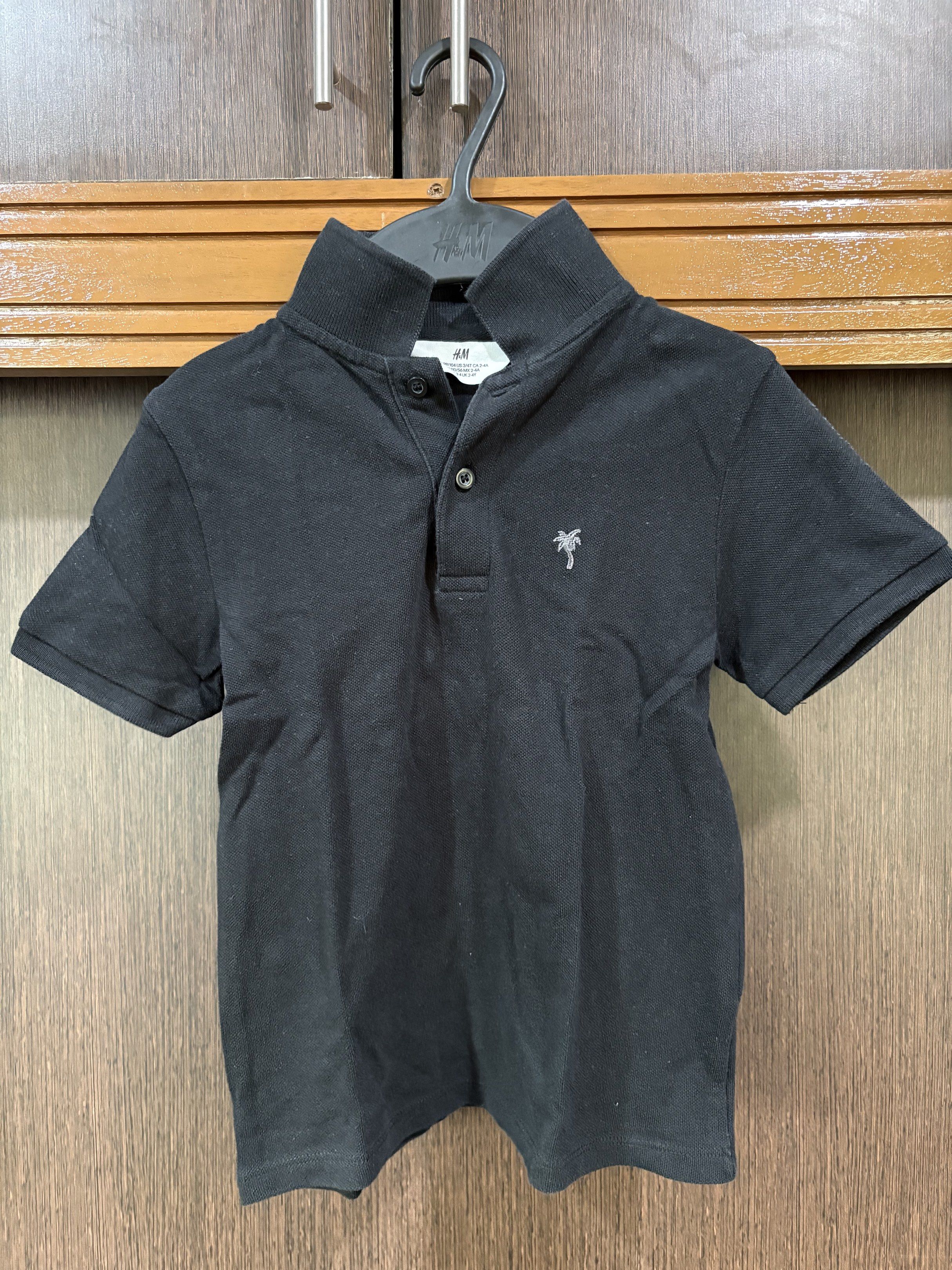 H&M Black Polo Shirt (Category: Babies & Kids Fashion) located in Manila. Submitted by purple-bunny-lizzie (Listing ID 1417312165, Image 1). Description: - H&M black polo shirt - High collar - Short sleeves - Small palm tree logo on chest - Two-button neckline -Size 98/104.