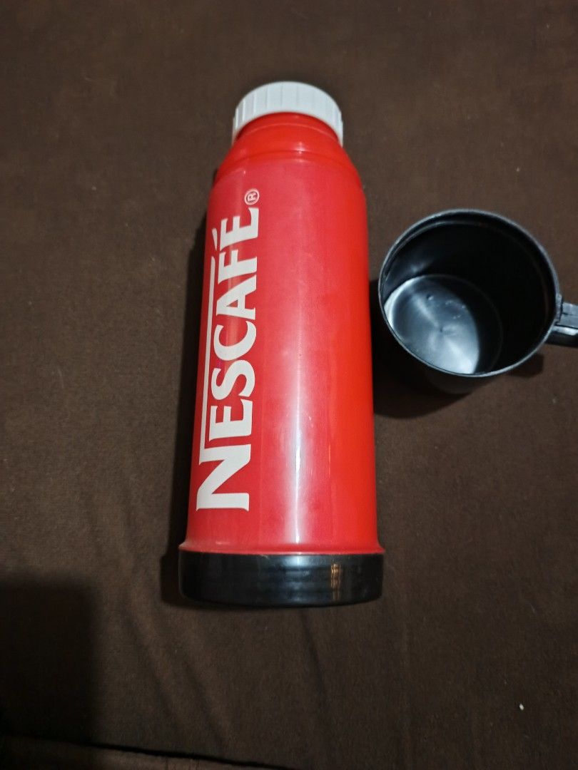 Nescafe Thermos with Cup (Category: Coffee & Tea Tableware) located in Caloocan City. Submitted by djfedz (Listing ID 1417237327, Image 2). Description: - Vintage red Nescafe thermos - Includes black plastic cup - Cylindrical design with black base and top - Features prominent white Nescafe logo - Ideal for coffee enthusiasts and collectors.