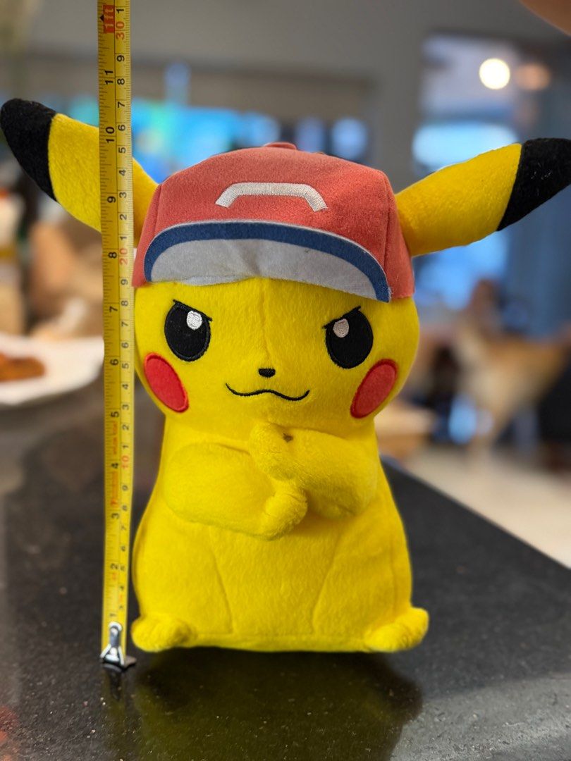 Pokemon Pikachu Plush Ash Cap (Category: Plushies & Soft Toys) located in Paranaque City. Submitted by thirdys_locker (Listing ID 1417314797, Image 3). Description: - Authentic Pikachu plush toy - Features a red cap with white and blue brim - Approximately 25cm tall - Includes Crane King and Banpresto tag - Tag features Pikachu and Ash - Yellow plush with black ears and red cheeks.