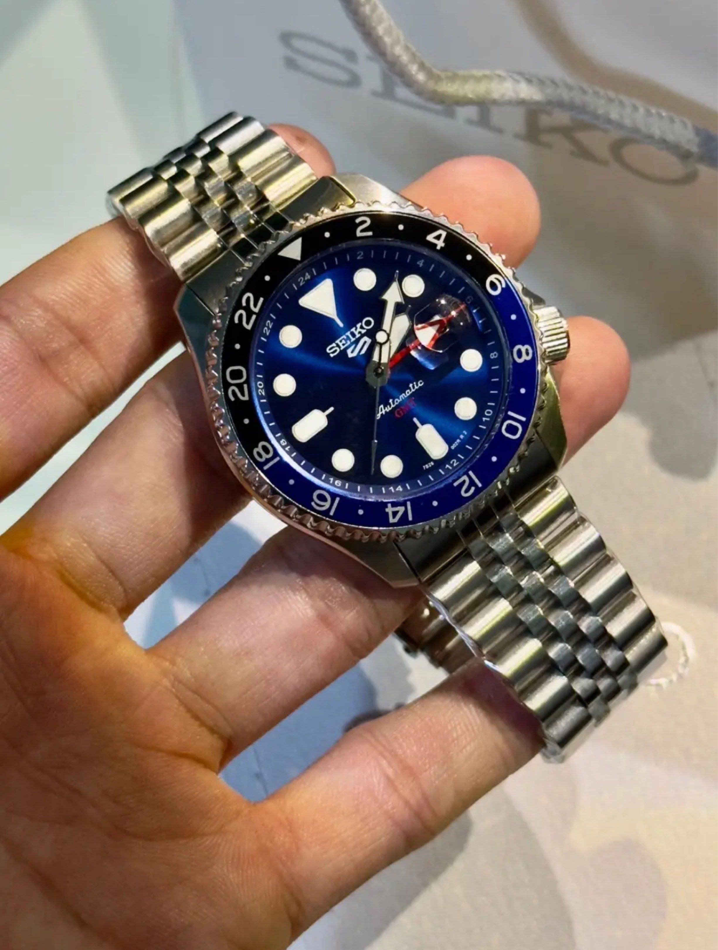 Seiko 5 GMT Automatic Watch (Category: Men's Watches) located in Pasay City. Submitted by cristerdaniel (Listing ID 1417391202, Image 1). Description: - Seiko 5 GMT automatic watch - Striking blue dial - Stainless steel bracelet - GMT bezel with 24-hour markings - Date display - Luminous hands and markers - Includes Seiko box.