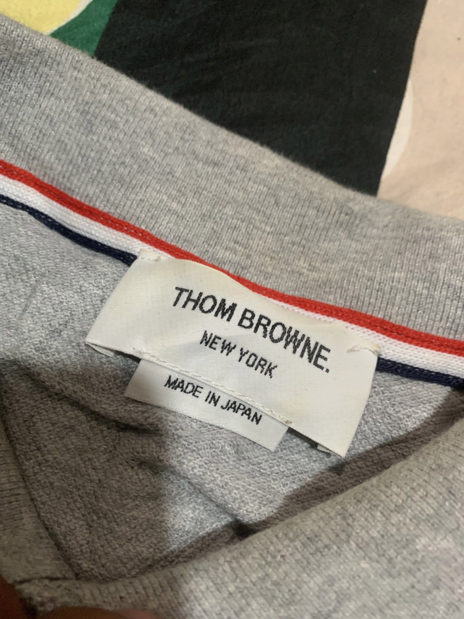 Thom Browne Grey Polo Shirt Size 3 (Category: Luxury Apparel) located in Cagayan de Oro. Submitted by agboysalis60090 (Listing ID 1417243075, Image 2). Description: Authentic Thom Browne polo shirt in grey. Features the signature red, white, and blue trim on the collar, pocket, and sleeves. Made in Japan. Size 3. Includes a chest pocket and button-up placket. The shirt has a classic polo design with short sleeves..