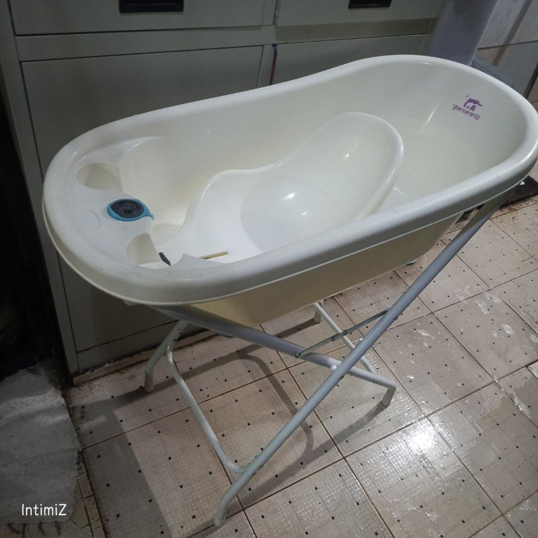Baby Bathtub with Stand (Category: Bathtub & Bath Accessories) located in Las Pinas. Submitted by mamshiejojo (Listing ID 1417442552, Image 1). Description: - Yomomma Baby bathtub with support -pink bath net - Includes a foldable metal stand - Off-white color - Features a drain for easy emptying.