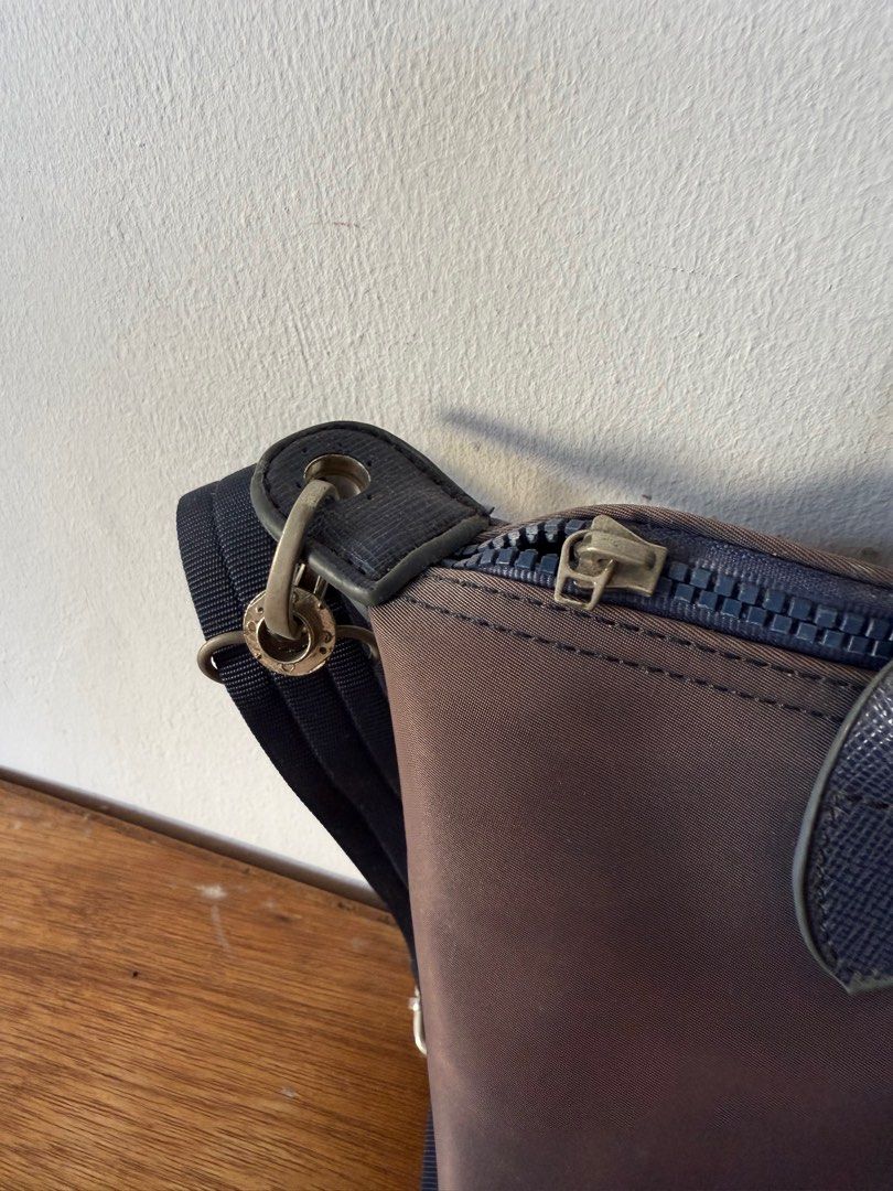 Longchamp Handbag with Shoulder Strap (Category: Luxury Bags & Wallets) located in Paranaque City. Submitted by garagesale0 (Listing ID 1417489648, Image 2). Description: - Authentic Longchamp handbag - Color: Brown body with navy blue accents - Navy blue shoulder strap - Top handle - Flap closure - Zipper closure - Silver-toned hardware - Navy blue interior - Signs of wear on handles.