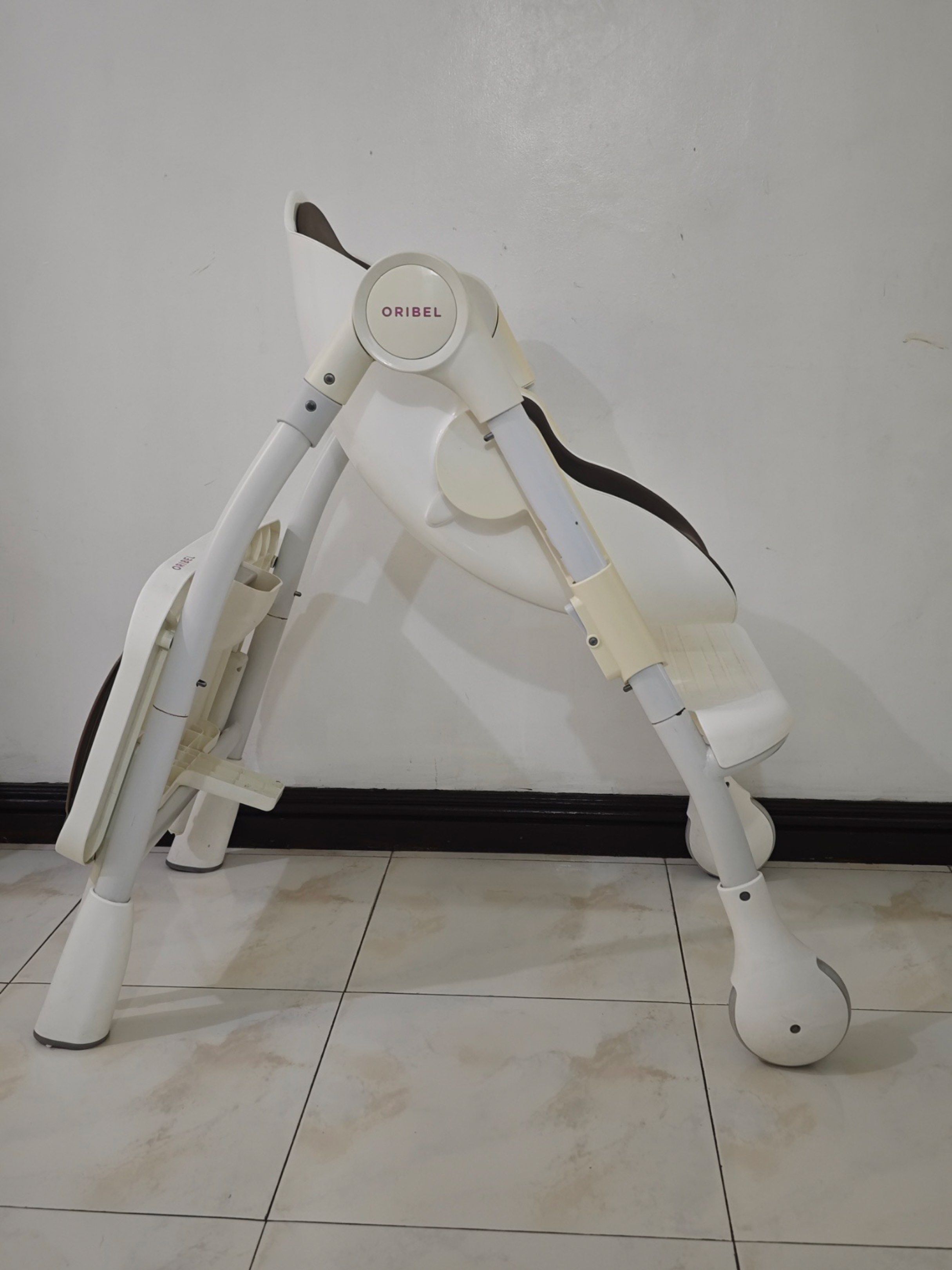 Oribel Cocoon High Chair (Category: Baby High Chairs) located in Paranaque City. Submitted by serendipity1021 (Listing ID 1417490535, Image 2). Description: Oribel Cocoon high chair with a brown and white color scheme. It features a tray, adjustable height, and a safety harness. The chair is foldable for easy storage. It has wheels for mobility. The seat is designed for comfort and support..
