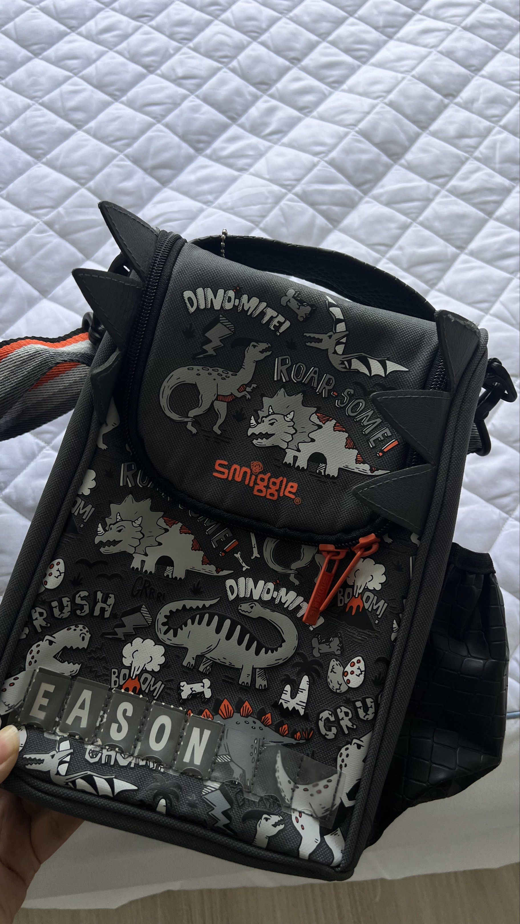Smiggle Junior Lunchbox - Dino-Mite! (Category: Food Organisation & Storage) located in Singapore. Submitted by clevercrystal_778635 (Listing ID 1417412426, Image 1). Description: Smiggle Junior Lunchbox with a fun dinosaur design. Features a name label, bottle sleeve, and adjustable shoulder strap. Includes a carry handle for easy transport. Perfect for school or outings..