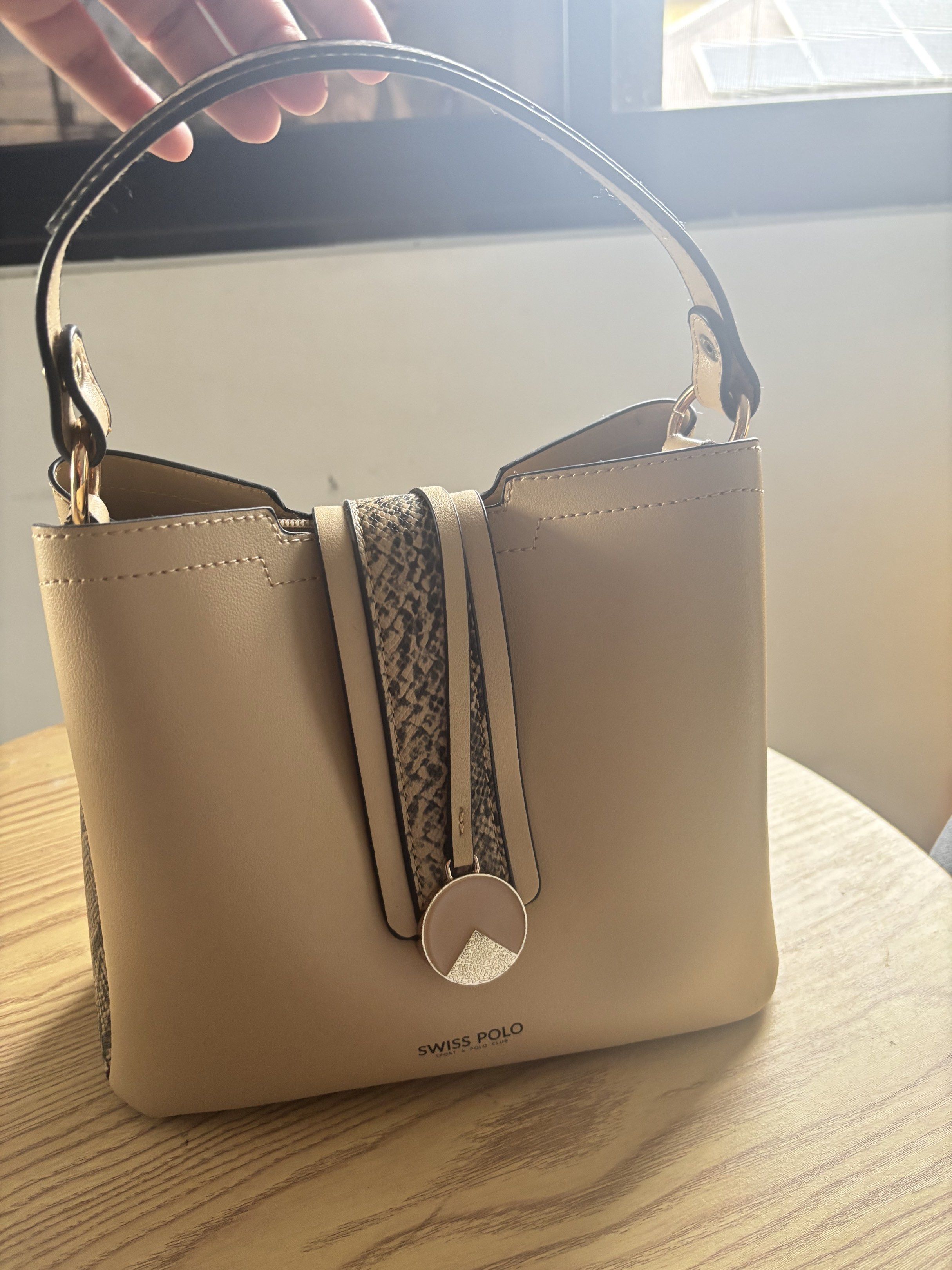 Swiss Polo Handbag (Category: Luxury Bags & Wallets) located in Bulacan. Submitted by mreyes21 (Listing ID 1417487239, Image 3). Description: - Swiss Polo handbag - Beige exterior with snakeskin pattern - Top handle - Includes a small, circular charm - Structured shape - Zippered interior compartment - Magnetic closure.