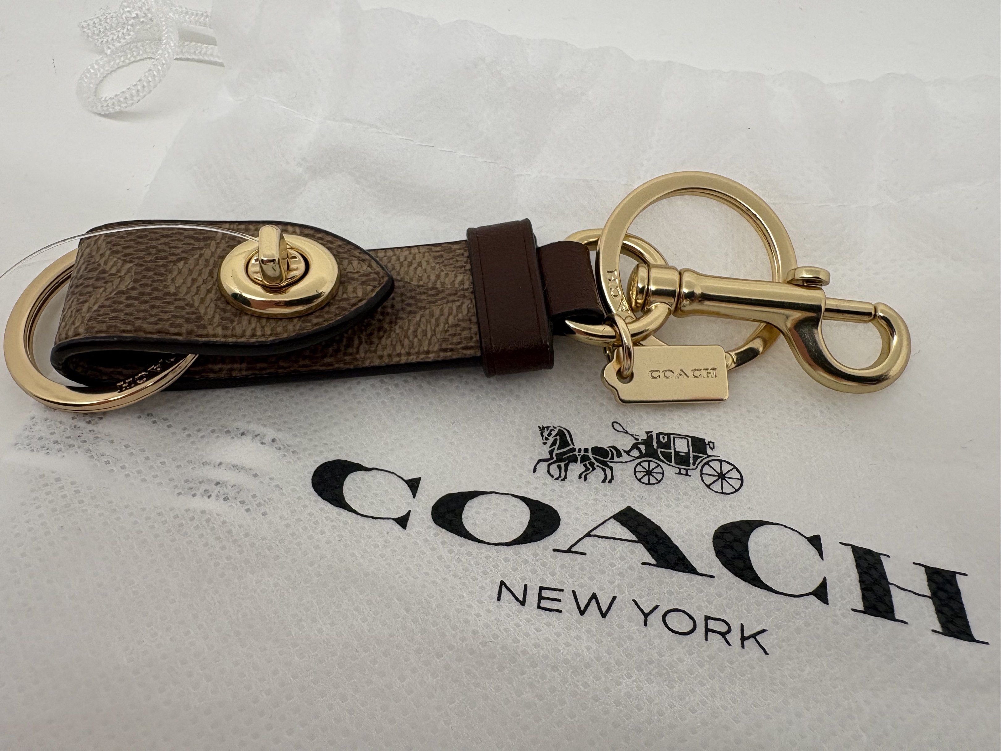 Coach Trigger Snap Bag Charm (Category: Luxury Accessories) located in Makati City. Submitted by harekrisha (Listing ID 1417663065, Image 1). Description: This is a Coach Trigger Snap Bag Charm in Signature coated canvas and refined calf leather with gold-tone hardware. It features a snap closure and a dogleash clip for attaching to a bag. It also includes attached split key rings. The dimensions are approximately 0.75” (L) x 2.5” (H). The style 