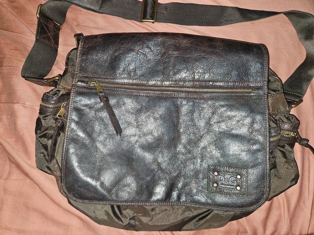 Dolce & Gabbana Messenger Bag (Category: Luxury Bags & Wallets) located in Quezon City. Submitted by preloveditems.qc (Listing ID 1417620395, Image 1). Description: - Authentic Dolce & Gabbana messenger bag -Sloutchy when worn - Dark brown leather flap and accents - Durable nylon body - Multiple zippered compartments for organization - Adjustable shoulder strap for comfortable wear - Spacious interior compartment - Iconic D&G logo on the front - 
