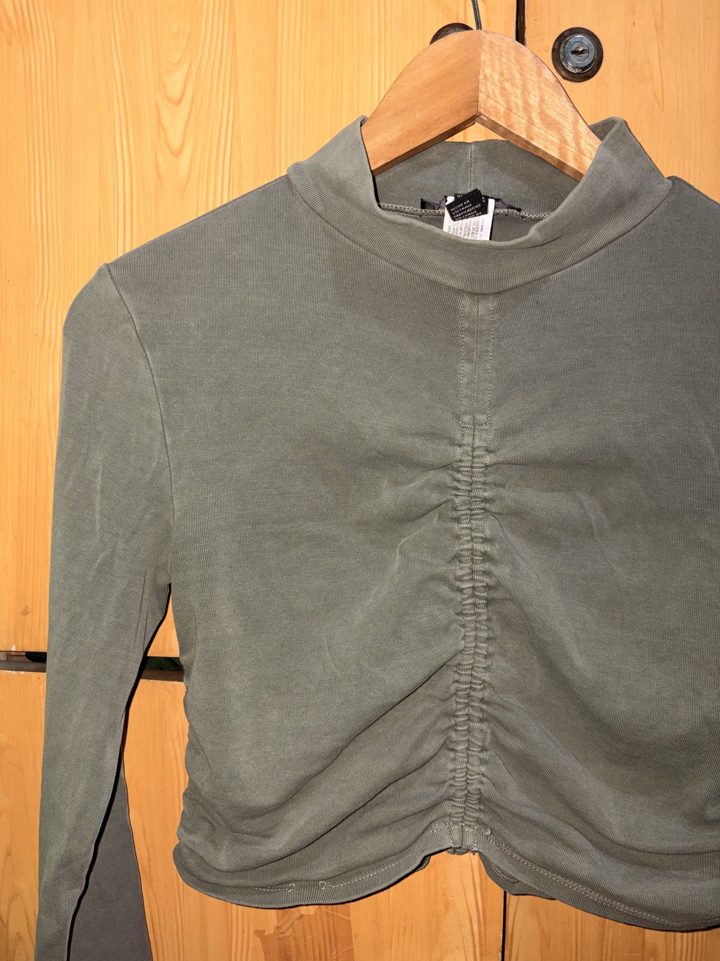 Forever 21 Olive Green Ruched Top (Category: Blouses) located in Manila. Submitted by ciiii1 (Listing ID 1417735731, Image 1). Description: Olive green long-sleeved top from Forever 21. Features a mock neck and ruched detailing down the front. The top is a cropped length. Size L. Made in Vietnam..