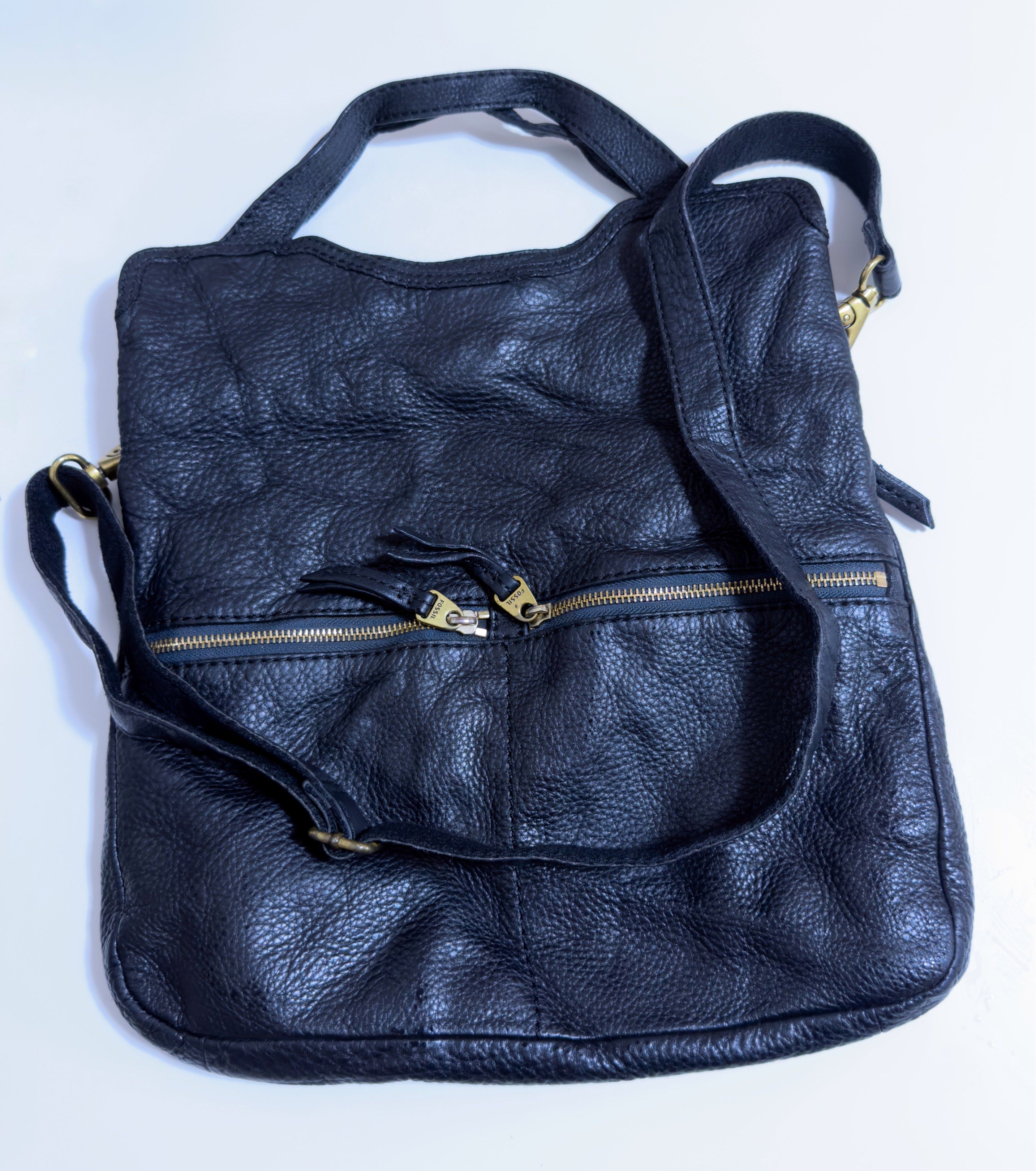Fossil Black Leather Shoulder Bag (Category: Shoulder Bags) located in Mandaluyong City. Submitted by gee028 (Listing ID 1417662373, Image 1). Description: Black leather shoulder bag from Fossil. Features a top handle and a detachable shoulder strap. Includes two front zippered pockets and a main compartment. The interior has a pocket and a Fossil logo. The bag has gold-toned hardware and a magnetic snap closure. The leather has a textured appear
