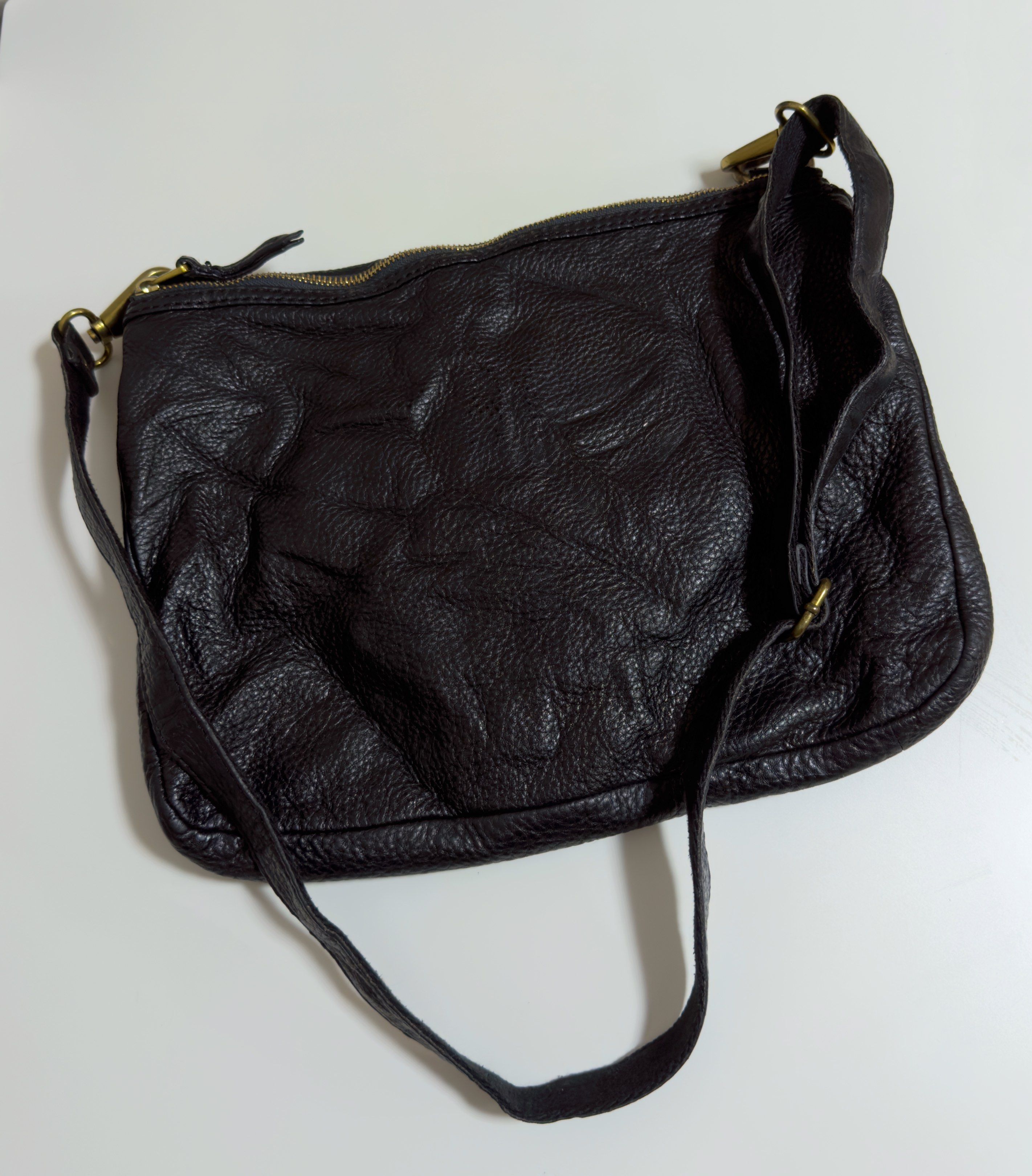 Fossil Black Leather Shoulder Bag (Category: Shoulder Bags) located in Mandaluyong City. Submitted by gee028 (Listing ID 1417662373, Image 3). Description: Black leather shoulder bag from Fossil. Features a top handle and a detachable shoulder strap. Includes two front zippered pockets and a main compartment. The interior has a pocket and a Fossil logo. The bag has gold-toned hardware and a magnetic snap closure. The leather has a textured appear