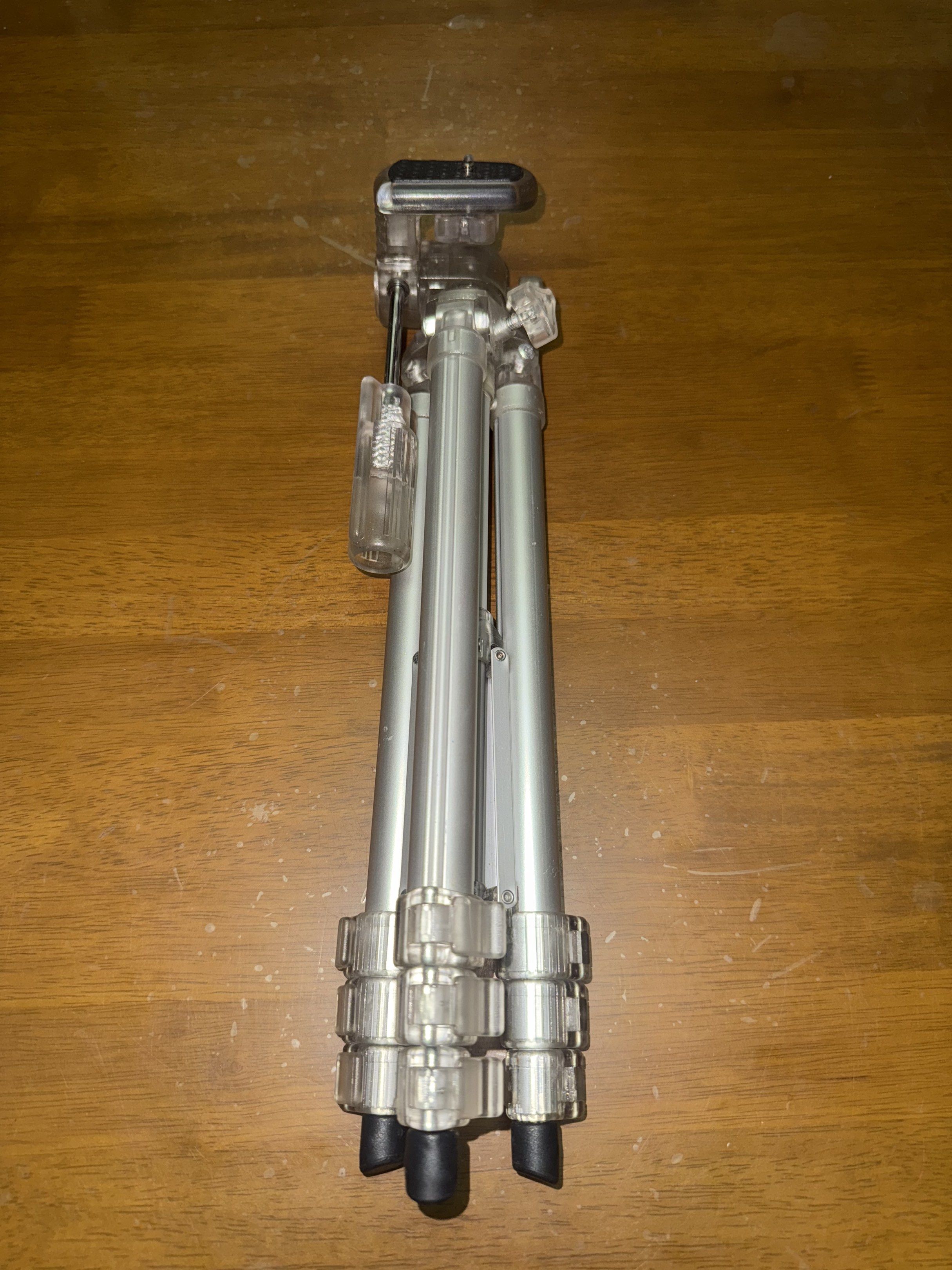Kenko SK-100 Tripod (Category: Tripods & Monopods) located in Pilar. Submitted by faveanyshop (Listing ID 1417654665, Image 2). Description: Kenko SK-100 tripod. It has a silver and clear plastic design. The tripod legs are adjustable and have clear plastic locking mechanisms. The head has a mounting plate for a camera. It is lightweight and portable, suitable for various photography needs. The tripod can be extended to a considerable height..