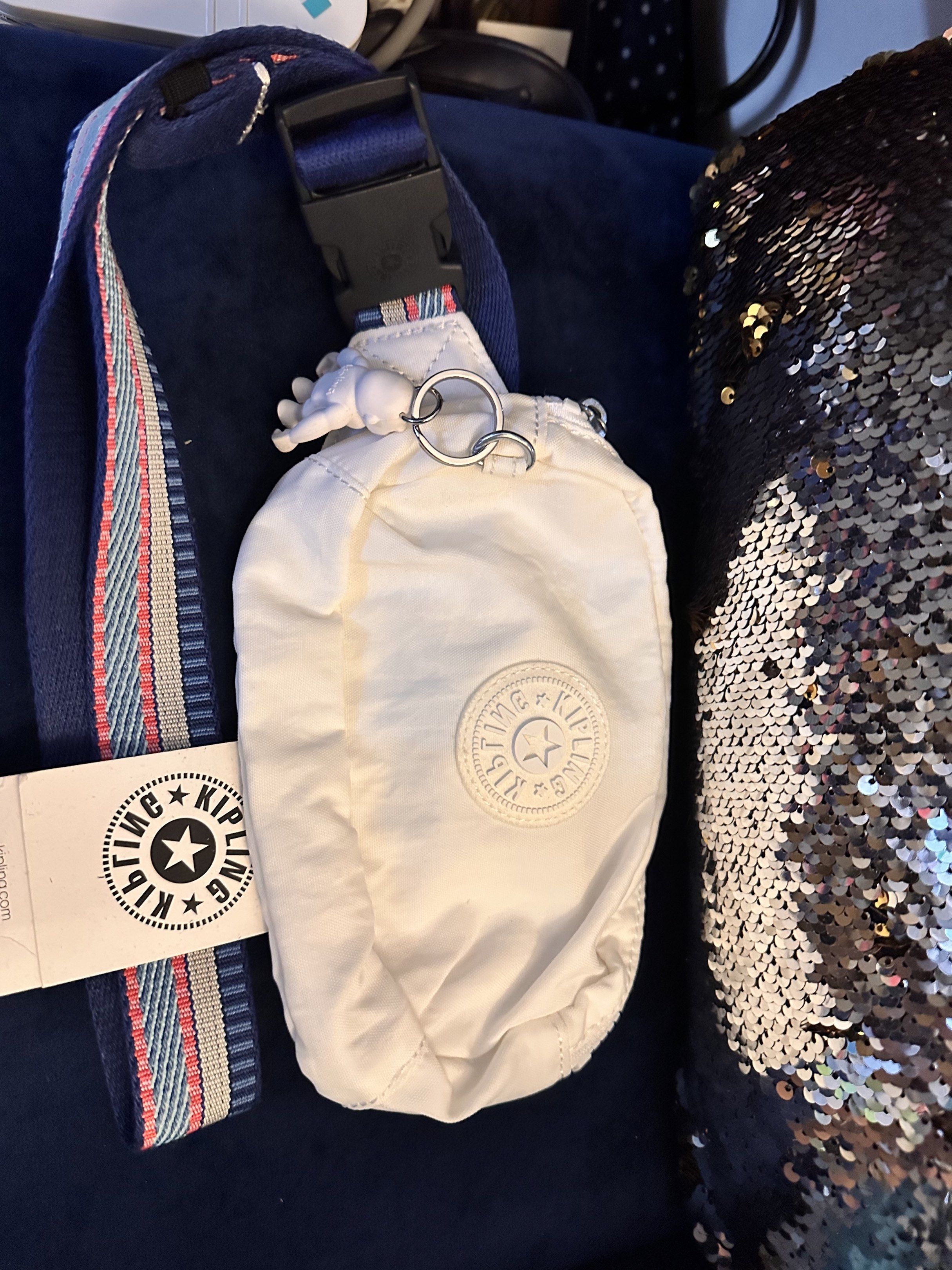 SALE!!! Kipling White Sling Bag (Category: Cross-body Bags) located in Manila. Submitted by youngdolphin-00c7ca (Listing ID 1417791274, Image 2). Description: - Kipling sling bag - White exterior and interior - Zip closure - Patterned strap - Kipling logo detail - Includes a small keychain .