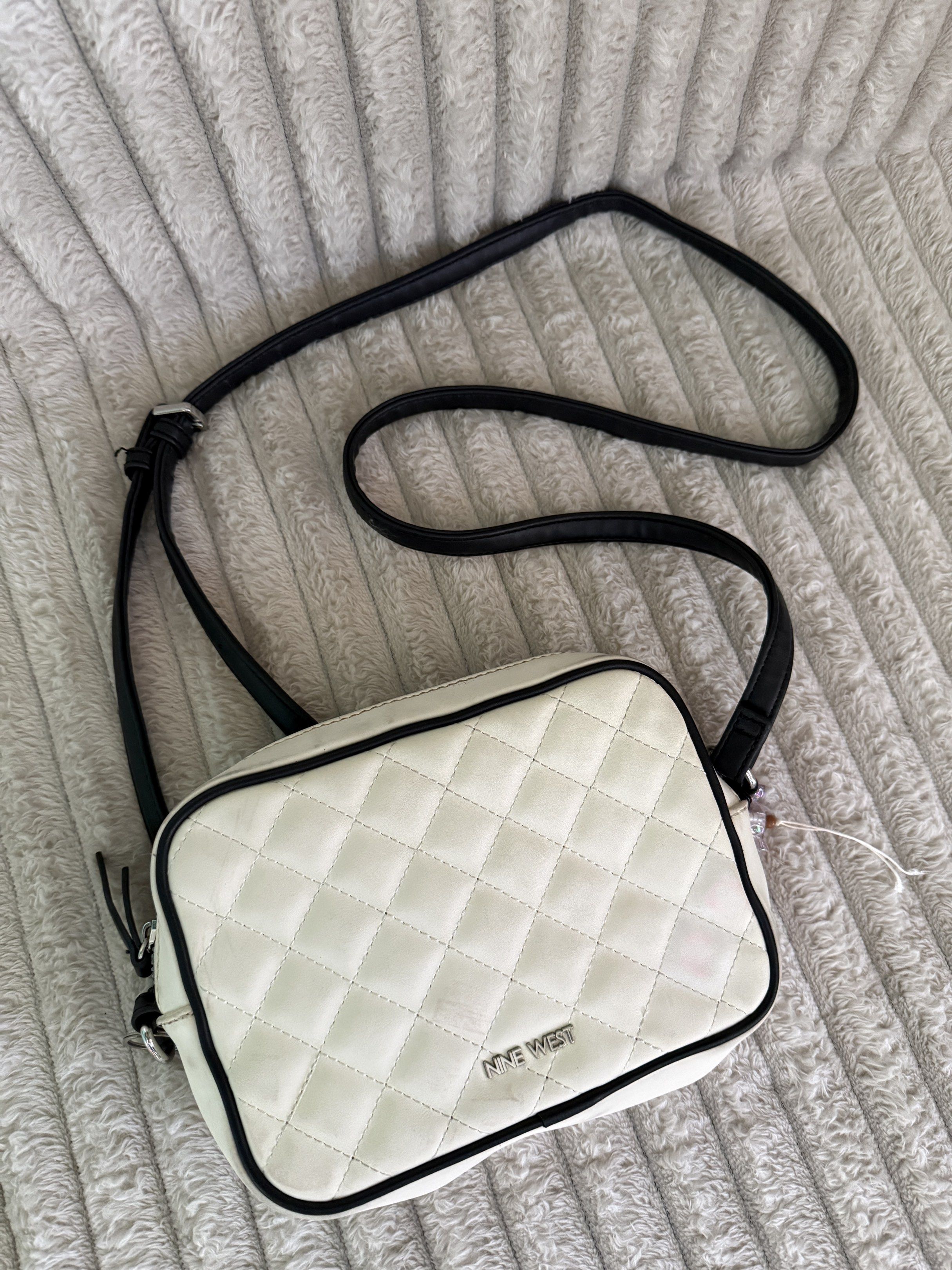 Nine West Quilted Crossbody Bag (Category: Cross-body Bags) located in Quezon City. Submitted by jcmelbs (Listing ID 1417706248, Image 1). Description: - Nine West crossbody bag - Quilted white exterior with black trim - Adjustable black strap - Zippered main compartment - Light-colored interior lining - Nine West label inside.