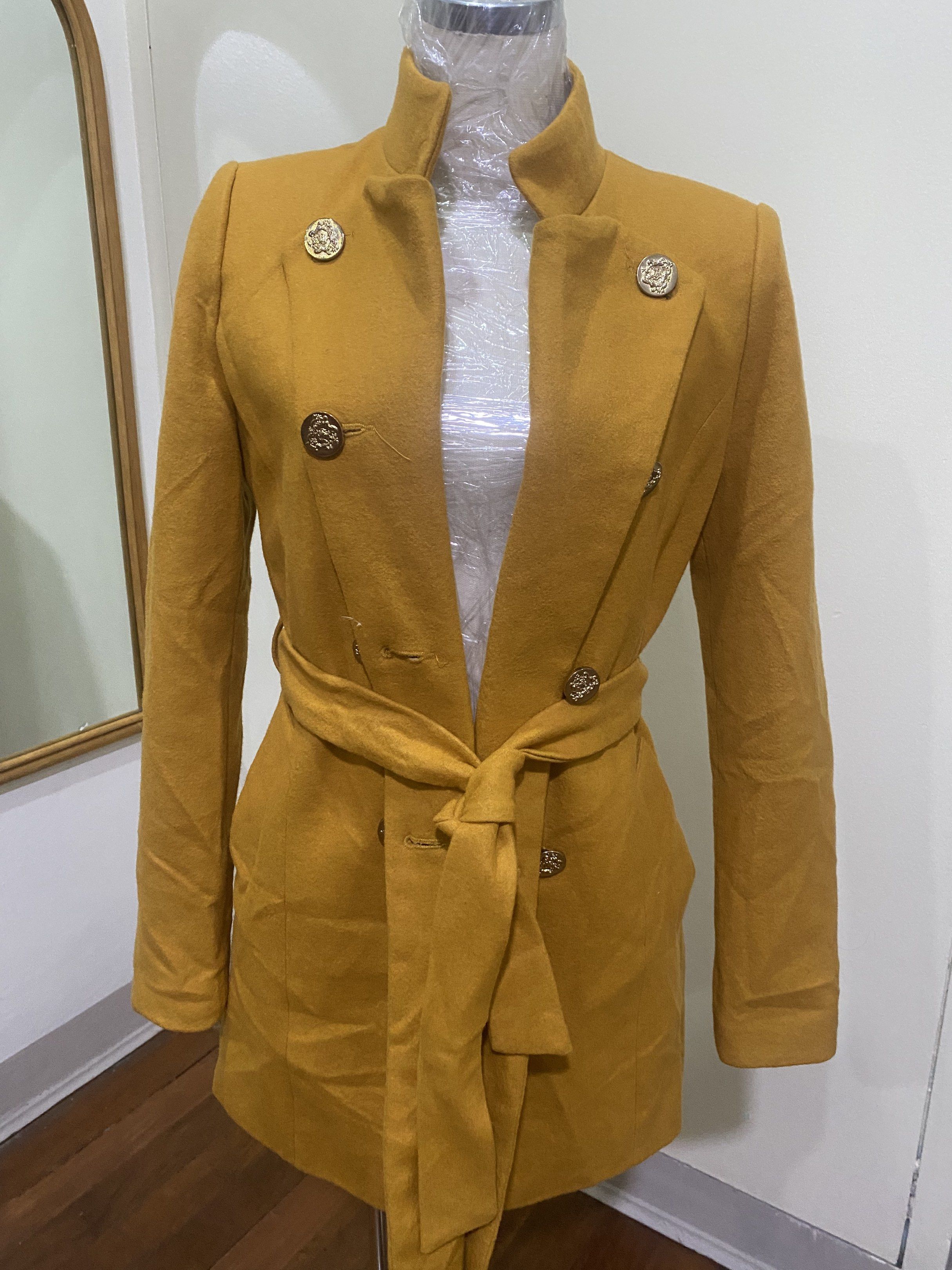 Ssemienne Korean Coat with Belt (Category: Coats, Jackets and Outerwear) located in Manila. Submitted by roseluxuryitems (Listing ID 1417726336, Image 3). Description: - Ssemienne mustard yellow coat - Size: S - Stand-up collar - Double-breasted with gold buttons - Includes matching belt - Quilted lining - Made in Korea.