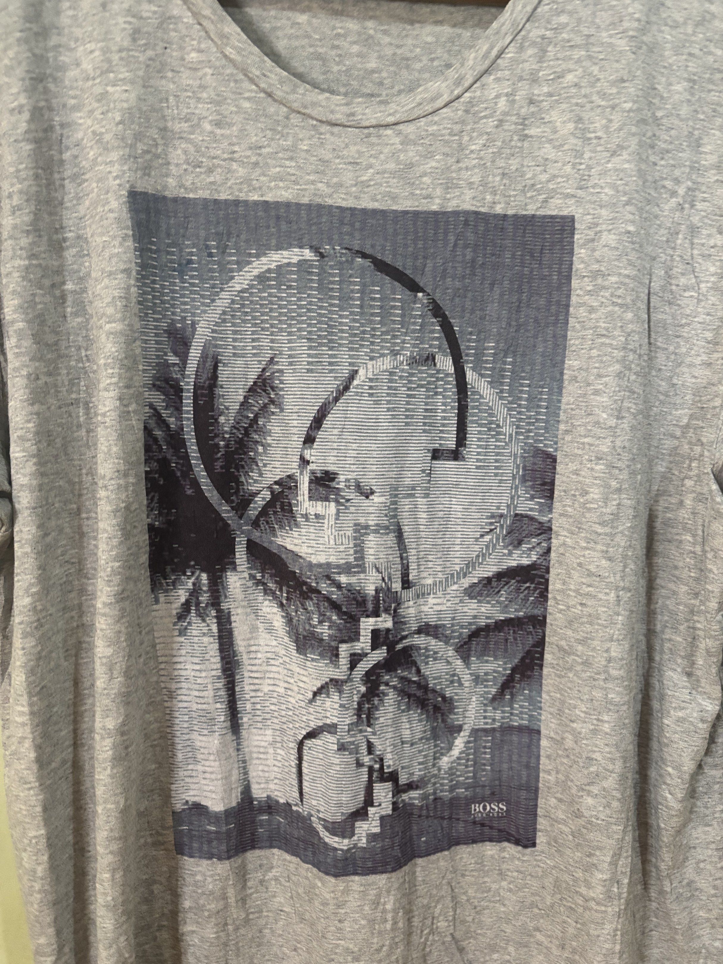 Authentic Hugo Boss Graphic Print T-Shirt (Category: Tshirts & Polo Shirts ) located in Tayabas. Submitted by mandothriftss (Listing ID 1417848743, Image 2). Description: Hugo Boss T-shirt in gray with a graphic print. Features a crew neck and short sleeves. The size is XXL. Measurements are W22.5 L28. Made of 100% cotton. Regular fit. Includes the Hugo Boss logo on the front and the tag..