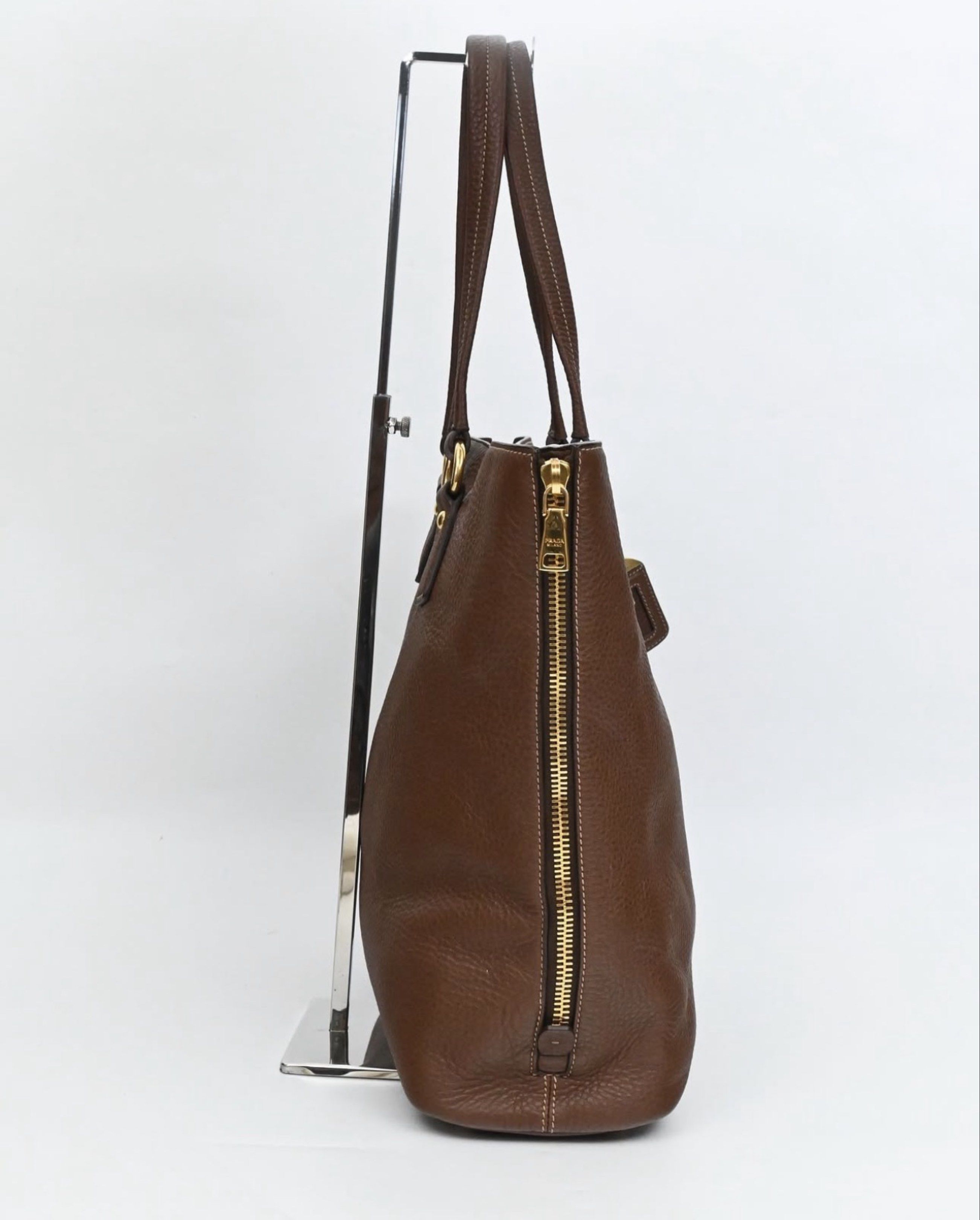 AUTHENTIC Prada Brown Leather Tote Bag (Category: Luxury Bags & Wallets) located in Manila. Submitted by itsmecamieeee (Listing ID 1417988117, Image 3). Description: - Authentic Prada tote bag - Brown leather exterior (Smooth and no cracks) - Gold-tone hardware (Hardware still goldish) - Zip closure (Still goldish) - Structured shape with flat base - Prada-branded interior lining - Detachable leather tag - Includes dust bag - No flaws - Negotiabl