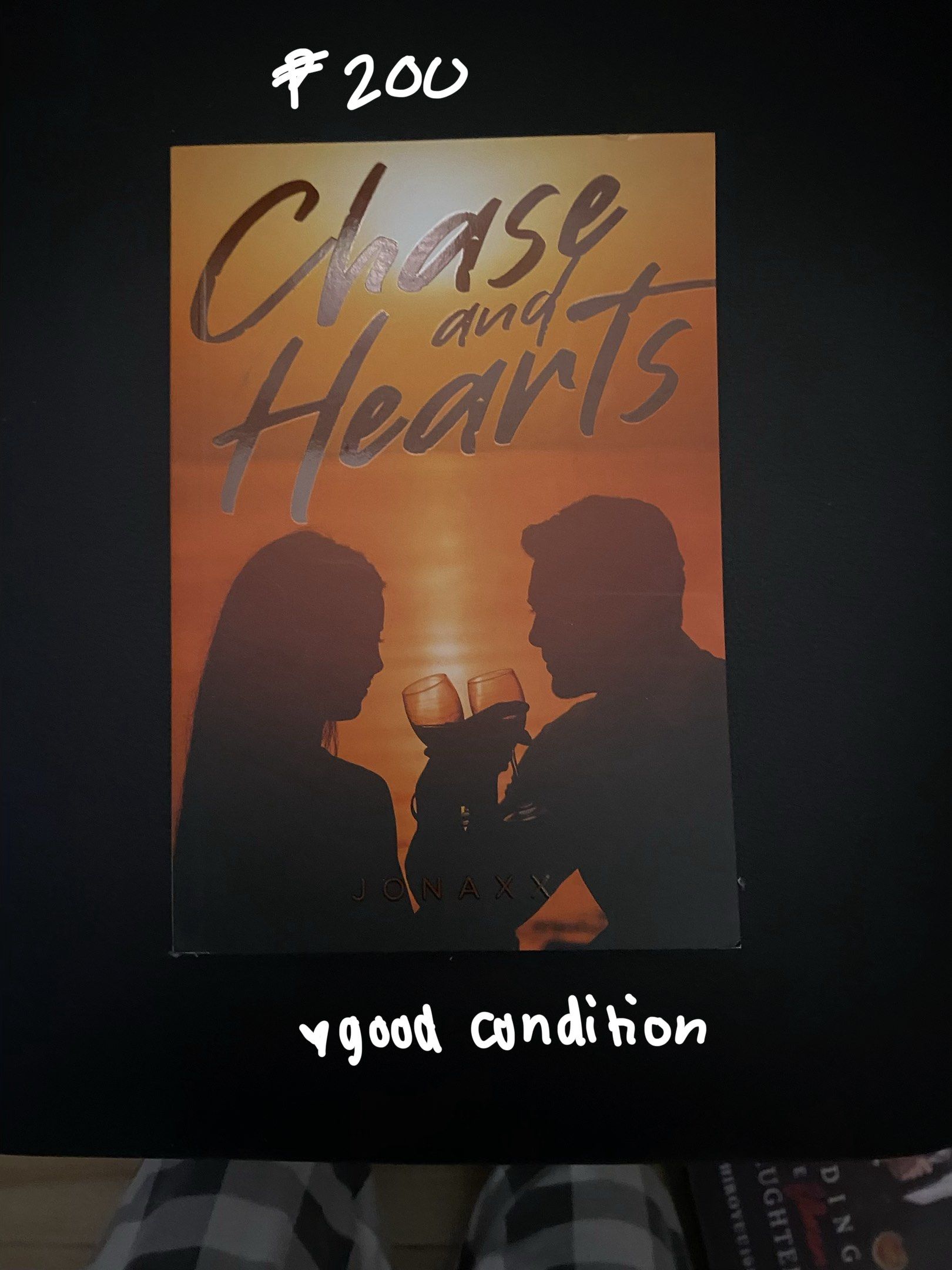 Chase and Hearts Book (Category: Storybooks) located in Pasig City. Submitted by rubyxoya (Listing ID 1417933003, Image 1). Description: - "Chase and Hearts" by Jonaxy available. - Cover art: Silhouette of a couple toasting wine glasses against an orange sunset. - Perfect for fans of romance novels!.