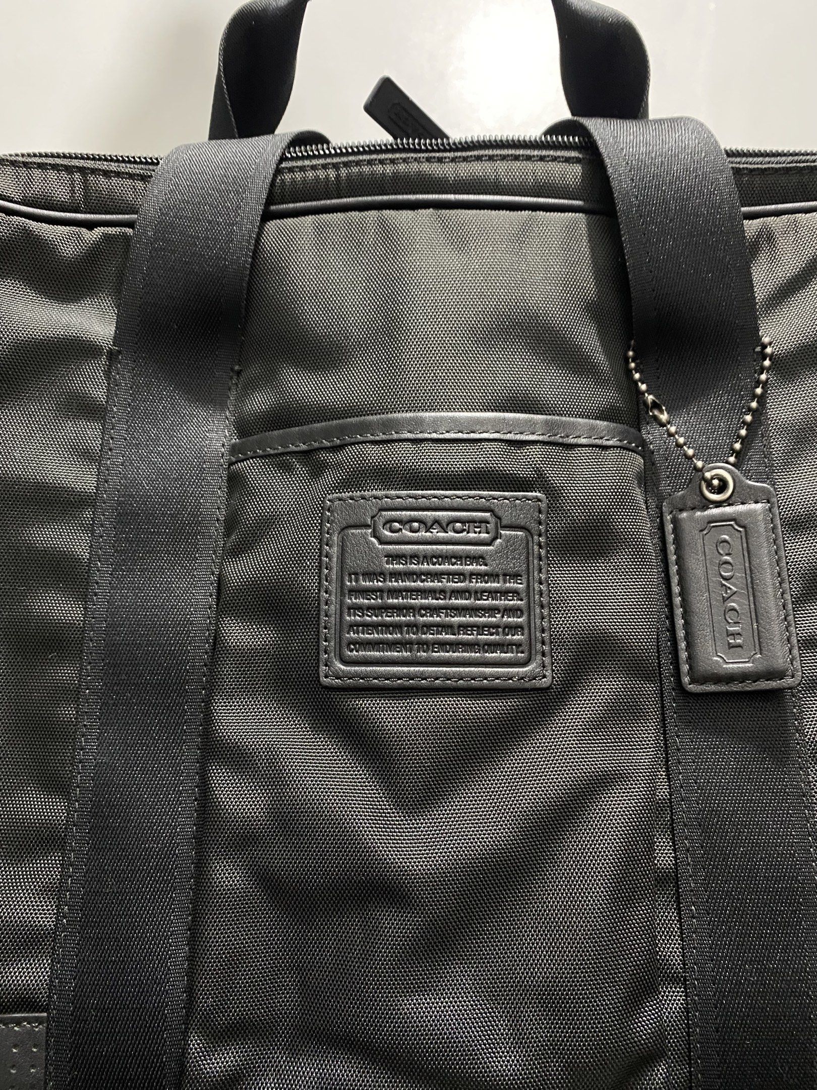 Coach Black Briefcase (Category: Briefcases) located in Cagayan de Oro. Submitted by cu_2022 (Listing ID 1417992831, Image 3). Description: Black Coach sling bag with a top handle and a detachable shoulder strap. Features a main compartment with multiple pockets and a zippered closure. Includes a Coach leather tag and a Coach logo on the front. The bag has a sleek, professional design, suitable for carrying documents and other essentials..