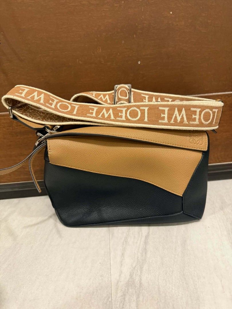 Loewe Puzzle Bag with Shoulder Strap (Category: Luxury Bags & Wallets) located in Camalig. Submitted by nasayaocat86662 (Listing ID 1417826910, Image 1). Description: - Loewe Puzzle Bag - Color block design: Black and tan leather - Detachable tan shoulder strap - Loewe logo on strap - Flap closure.