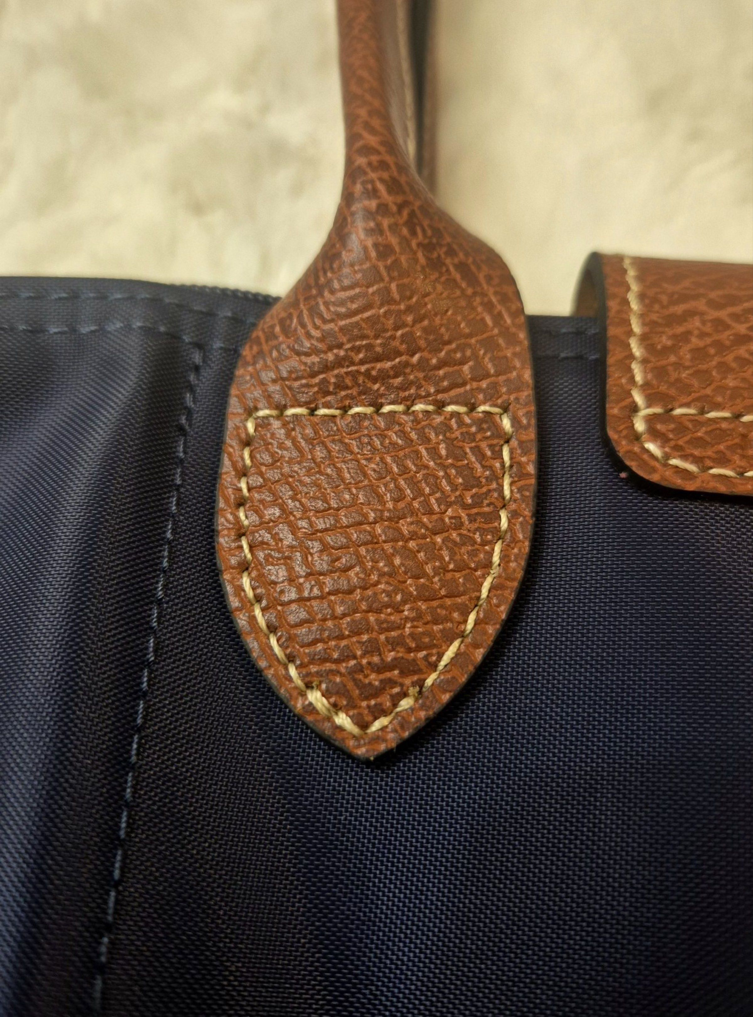 Longchamp Le Pliage Tote Bag (Category: Luxury Bags & Wallets) located in Marilao. Submitted by paulasia87 (Listing ID 1416862783, Image 3). Description: - Navy blue Longchamp Le Pliage tote bag - Brown leather handles and flap - Gold-tone button closure - Includes Longchamp paper bag and card.