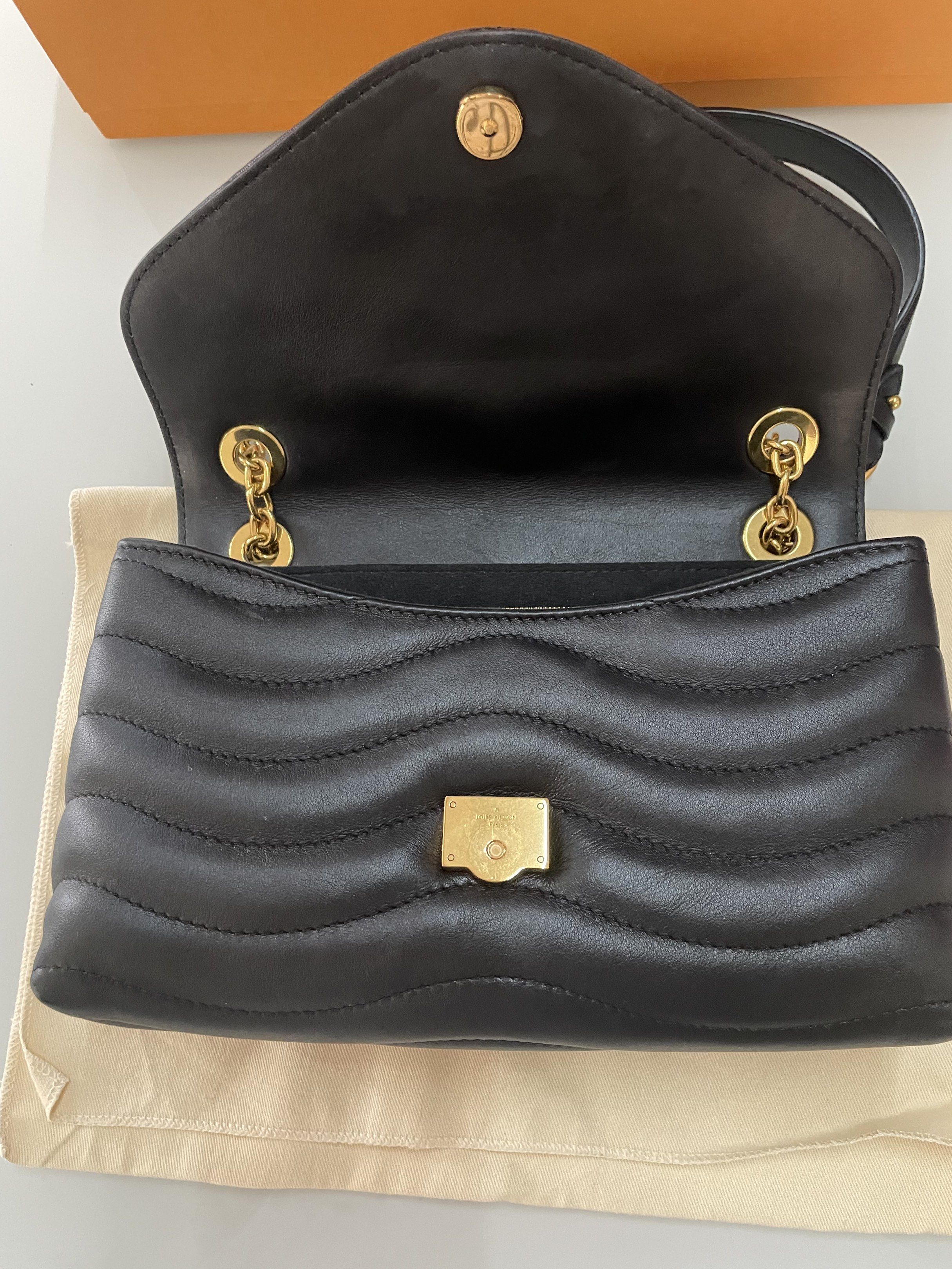 Louis Vuitton New Wave Chain Bag Black (Category: Luxury Bags & Wallets) located in Taguig. Submitted by declutteringmom314 (Listing ID 1417864752, Image 2). Description: Authentic Louis Vuitton New Wave Chain Bag in black. Features a quilted design with a gold-tone LV logo on the front. Includes a chain strap with a leather shoulder rest. Comes with original box, dust bag, and shopping bag. The interior has a zip pocket. The zipper pull has the 
