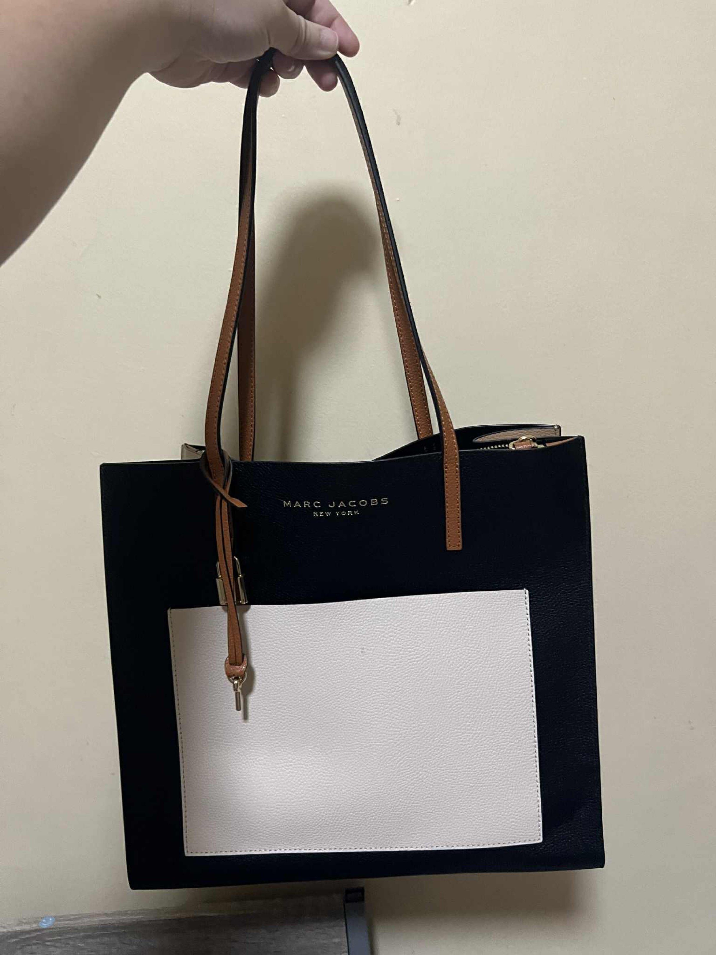 Marc Jacobs Tote Bag (Category: Tote Bags) located in Manila. Submitted by lat0821 (Listing ID 1417951709, Image 1). Description: - Black tote bag - White front pocket - Brown leather handles - Zipper closure in the middle - Marc Jacobs logo - Stylish and functional for everyday use -manage your expectation as this is slightly used. -used 3x, not properly stored.
