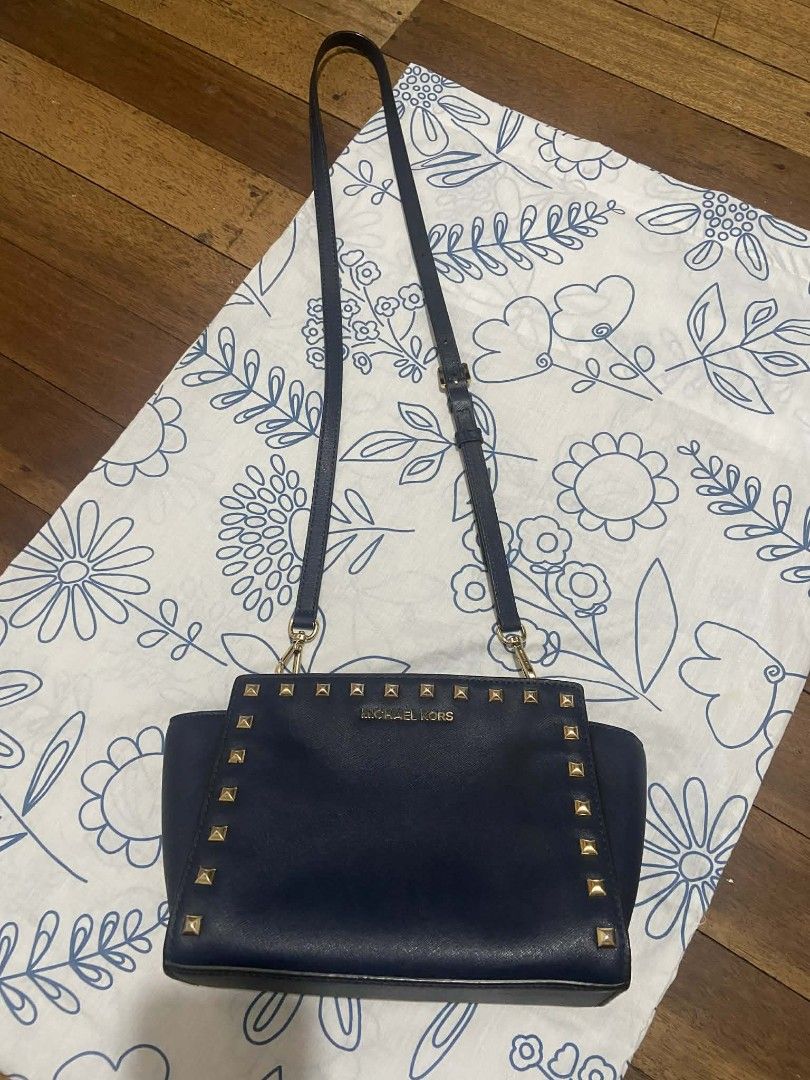 Michael Kors Studded Shoulder Bag (Category: Luxury Bags & Wallets) located in Taytay. Submitted by itscolsie (Listing ID 1417965350, Image 1). Description: - Navy blue Michael Kors shoulder bag - Gold-colored stud details - Adjustable long strap - Rectangular shape - Flap closure - Michael Kors logo on front - Smooth material message me for more info.