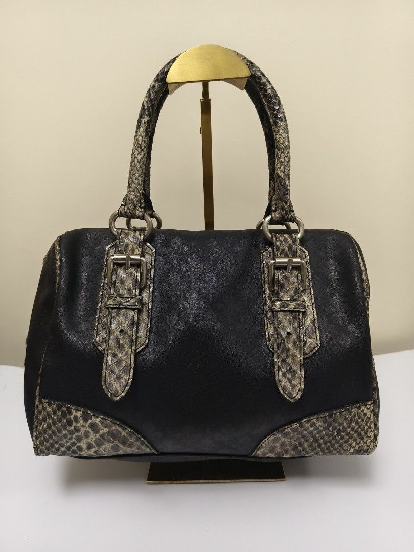 Patrick Cox Leather Snake Doctors Bag (Category: Luxury Bags & Wallets) located in Baguio. Submitted by PreiLoveMaria (Listing ID 1417973208, Image 2). Description: Patrick Cox handbag featuring the brand's signature fleur-de-lys (lily crest) logo pattern. The bag is a black satchel style with faux snakeskin accents on the handles, buckles, and bottom corners. 👜Good used condition with minimal flaw (needs stiching in the zipper about an inch. Pl