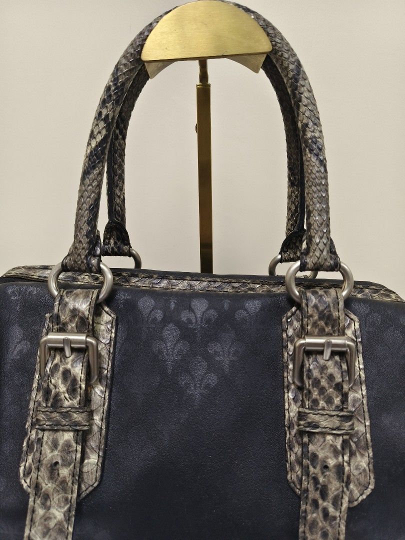 Patrick Cox Leather Snake Doctors Bag (Category: Luxury Bags & Wallets) located in Baguio. Submitted by PreiLoveMaria (Listing ID 1417973208, Image 3). Description: Patrick Cox handbag featuring the brand's signature fleur-de-lys (lily crest) logo pattern. The bag is a black satchel style with faux snakeskin accents on the handles, buckles, and bottom corners. 👜Good used condition with minimal flaw (needs stiching in the zipper about an inch. Pl
