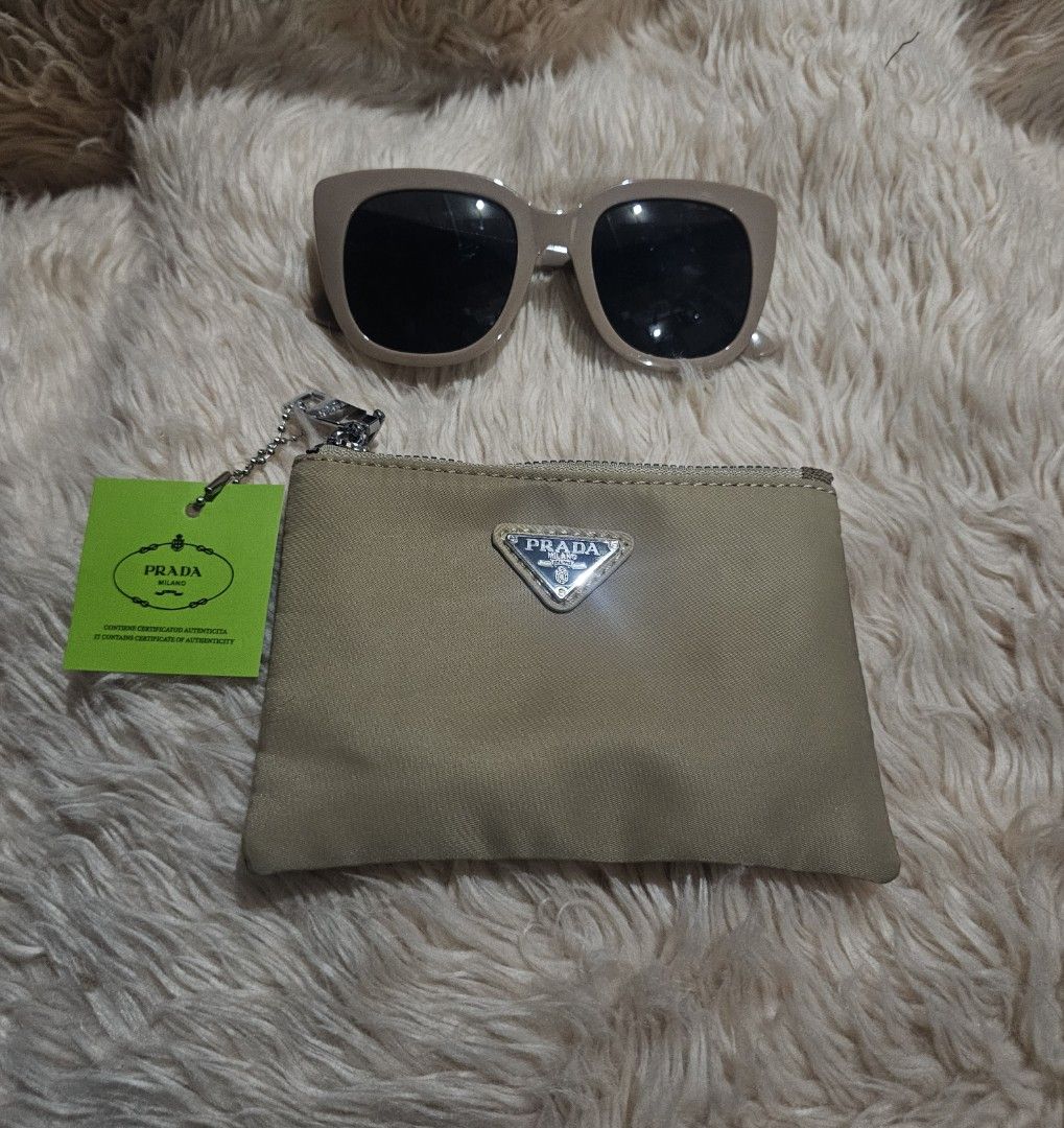 Prada Coin Purse with Tag (Category: Luxury Bags & Wallets) located in Manila. Submitted by lezahceni54686 (Listing ID 1417814595, Image 1). Description: - Prada coin purse - Beige canvas exterior - Silver Prada logo - Includes matching tag - Zipper closure - Small chain - Perfect for small essentials - Stylish and practical accessory -sunglasses not included for size reference only.
