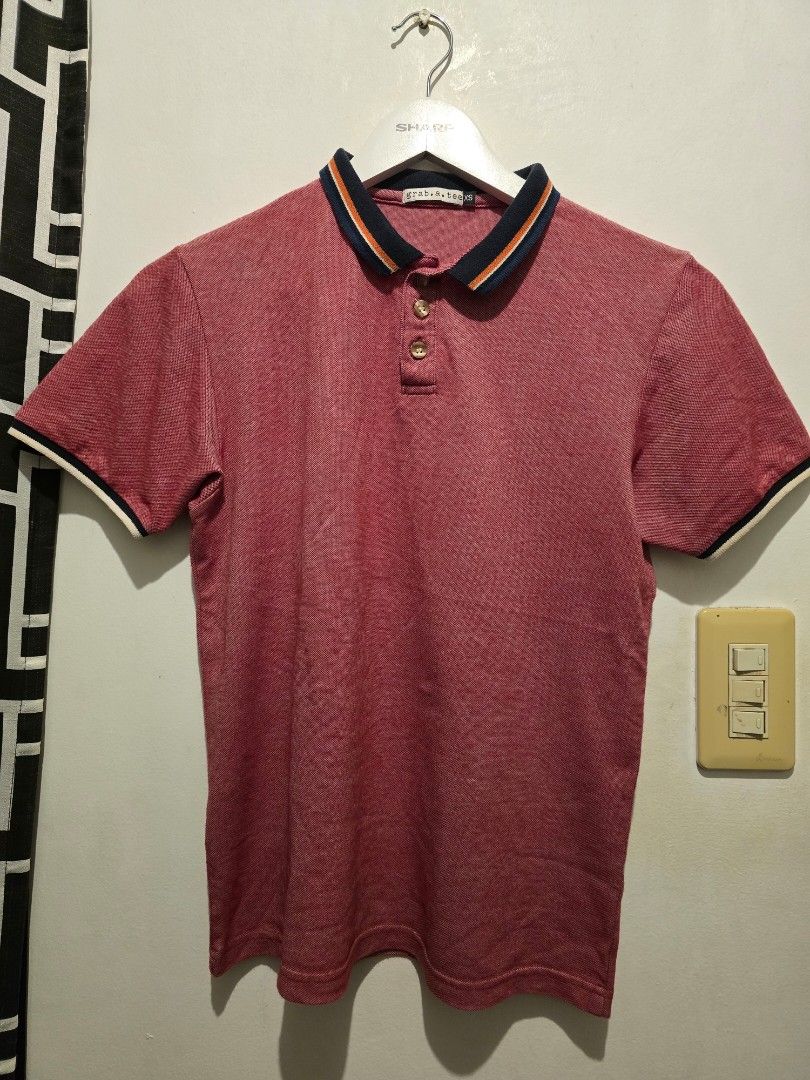 Red Polo Shirt with Striped Collar (Category: Tshirts & Polo Shirts ) located in Taguig. Submitted by bandsaccount (Listing ID 1417929944, Image 1). Description: - Classic red polo shirt - Collared neckline - Navy, orange, and white striped collar detail - White and navy sleeve trim - Button-up placket - Textured fabric - Versatile for casual wear.