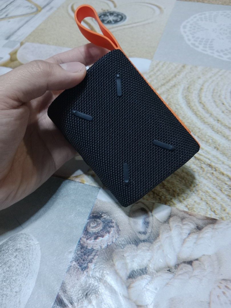 Xiaomi Portable Bluetooth Speaker (Category: Soundbars, Speakers & Amplifiers) located in Marikina City. Submitted by jameeeessssm (Listing ID 1417822153, Image 3). Description: - Xiaomi Mi Sound Pocket 5W portable Bluetooth speaker - Color: Black with orange strap - Features power and Bluetooth buttons - Mesh fabric design - Includes charging port - Xiaomi logo visible - Designed by Xiaomi.