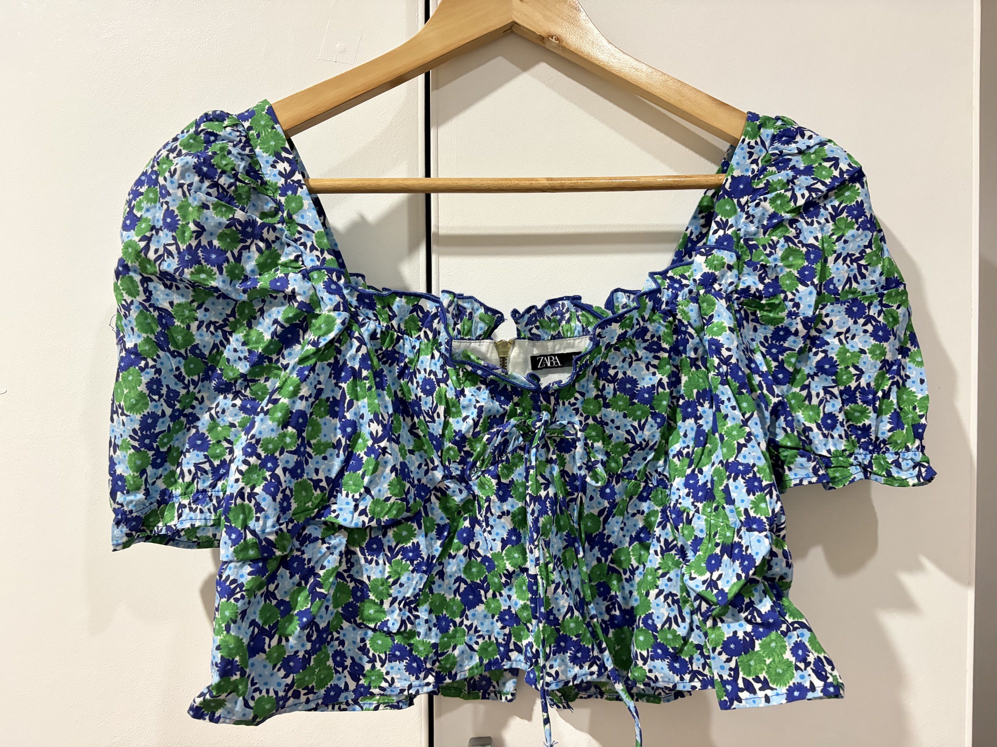 Zara Floral Puff Sleeve Top (Category: Blouses) located in Bacolod City. Submitted by kzyxa.d (Listing ID 1417970671, Image 1). Description: • Puff sleeves • Floral • Square neckline • Back zipper closure • Ruffled trim • Tie detail at front • Issue: NONE RFS: Declutter Location: Bacolod City .