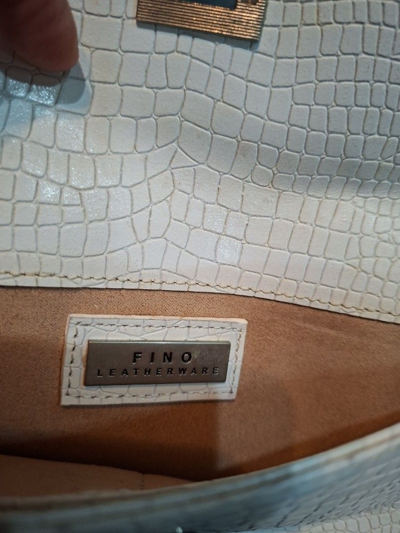 Fino Leatherware Clutch Bag (Category: Luxury Bags & Wallets) located in Quezon City. Submitted by apple.ana888 (Listing ID 1418075634, Image 3). Description: - Fino Leatherware clutch bag - Textured, off-white exterior - Secure clasp closure - Detachable wrist strap - Rectangular shape - Subtle embossed pattern - Interior: lighter shade (tan) - Ideal for special occasions or everyday use.
