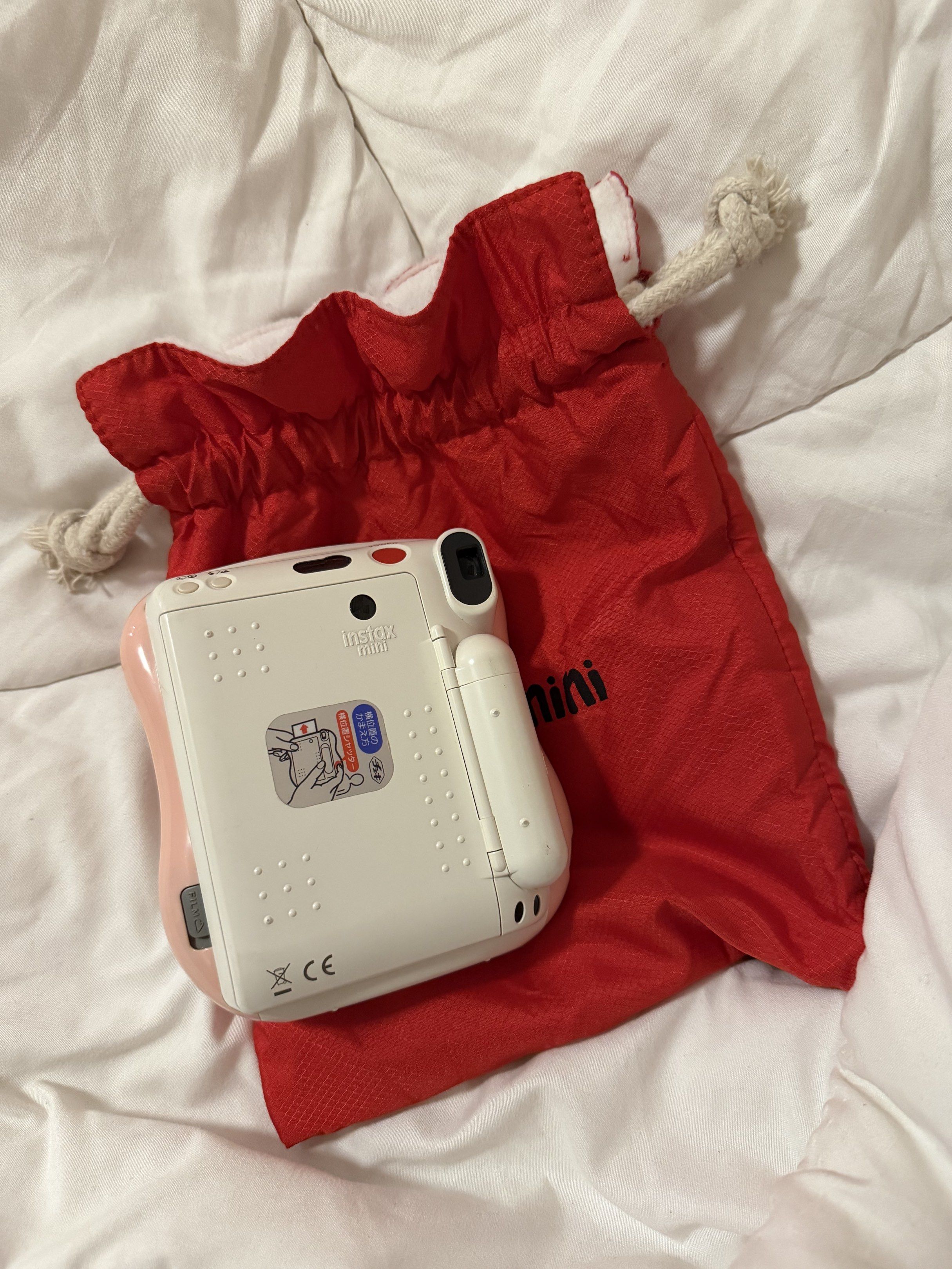Fujifilm Instax Mini 25 (Category: Cameras) located in Caloocan City. Submitted by mdowmya (Listing ID 1418037668, Image 2). Description: - Fujifilm Instax Mini instant camera - Color: White and Pink - Lens: 60mm focus range - Includes a red carrying bag - Bag closure: Drawstring - Uses CR2 batteries Issues: batteries need to be changed .