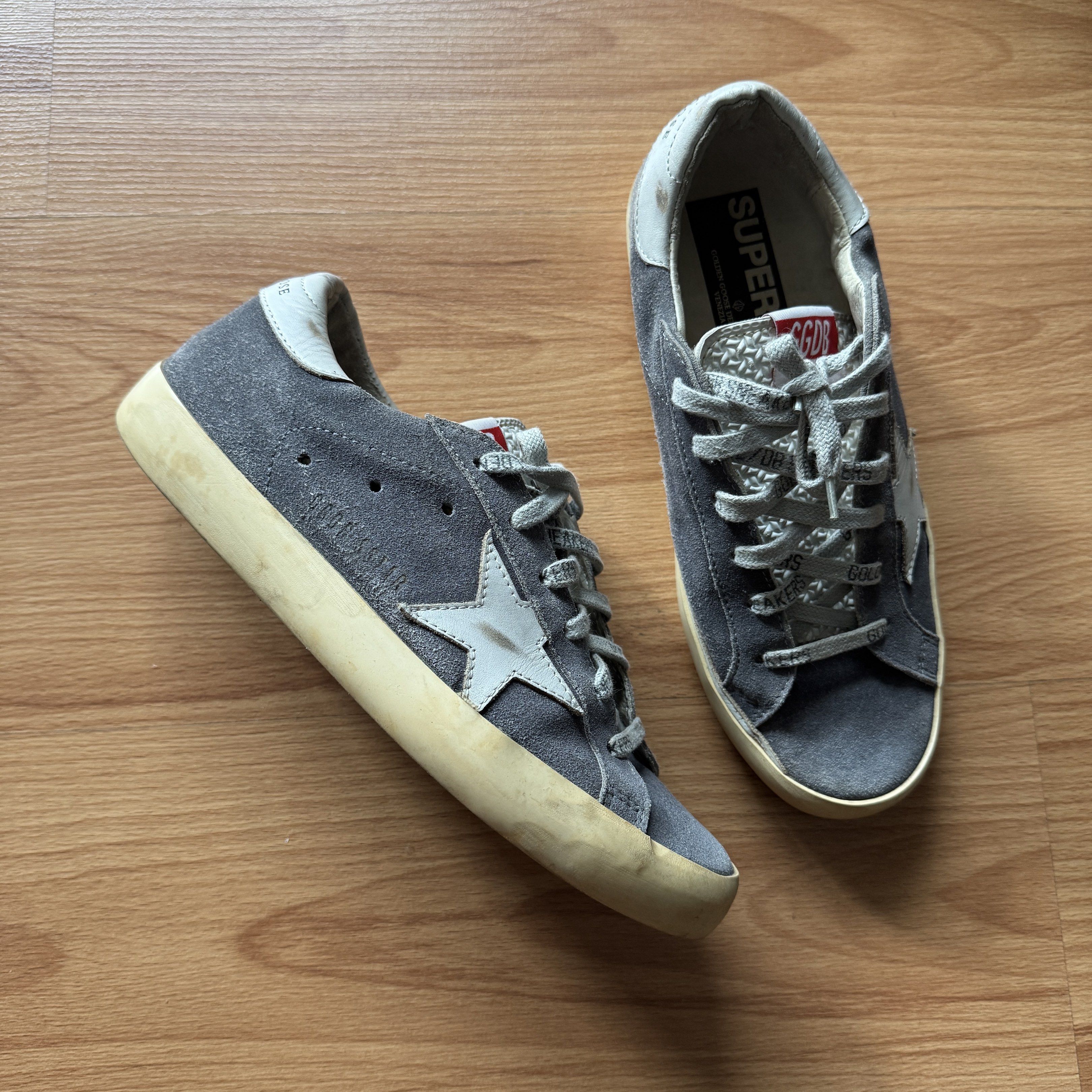 Golden Goose Superstar Sneakers (Category: Sneakers) located in Quezon City. Submitted by thingsforless (Listing ID 1418066440, Image 3). Description: - Golden Goose Superstar sneakers - Grey suede upper - White star detail - Cream-colored sole - White leather accents - Branded laces: "Golden Goose Sneakers" - Leather insole with Golden Goose Deluxe Brand logo - Size 37 24cm Fits US7.