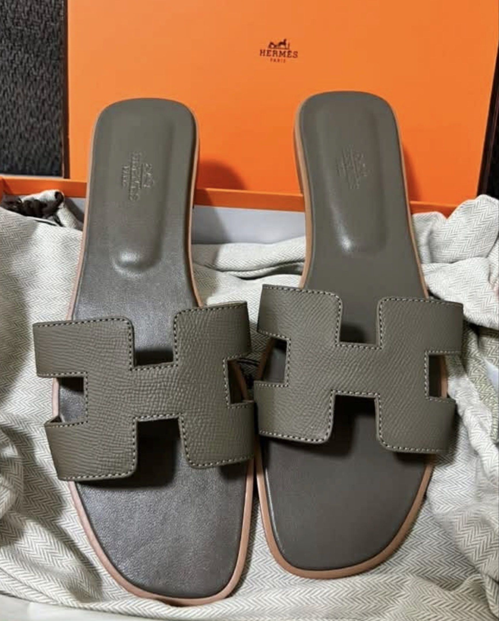 Hermes Oran Sandals etoupe (Category: Sneakers & Footwear) located in Manila. Submitted by rosmiemuno16247 (Listing ID 1418033234, Image 1). Description: - Authentic Hermes Oran sandals - Neutral grey color - Iconic 'H' cut-out design - Unworn condition - Includes original box - Light pink sole trim - Perfect for everyday wear.
