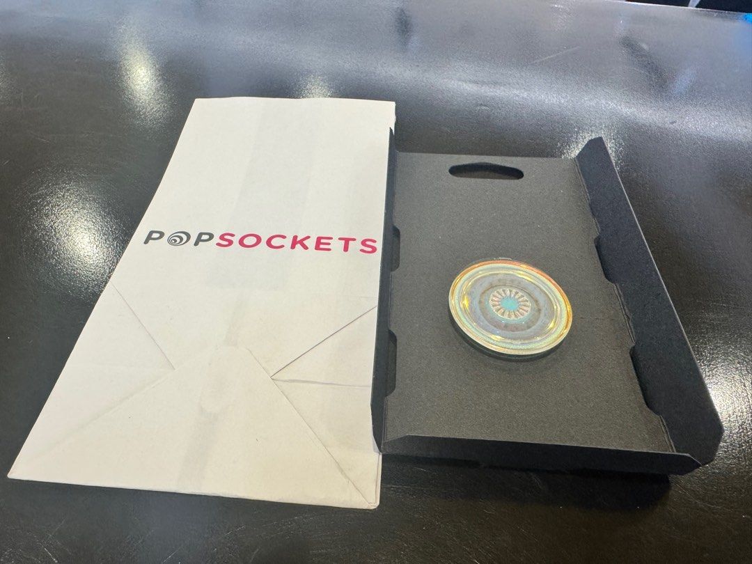 PopSockets Phone Grip (Category: Mounts & Holders) located in Manila. Submitted by shiki.ix (Listing ID 1418063137, Image 1). Description: - Iridescent PopSockets phone grip - Unused, in original packaging - Attaches to most phones, tablets, and cases - Provides a secure grip for texting, calling, and photos - Functions as a stand.