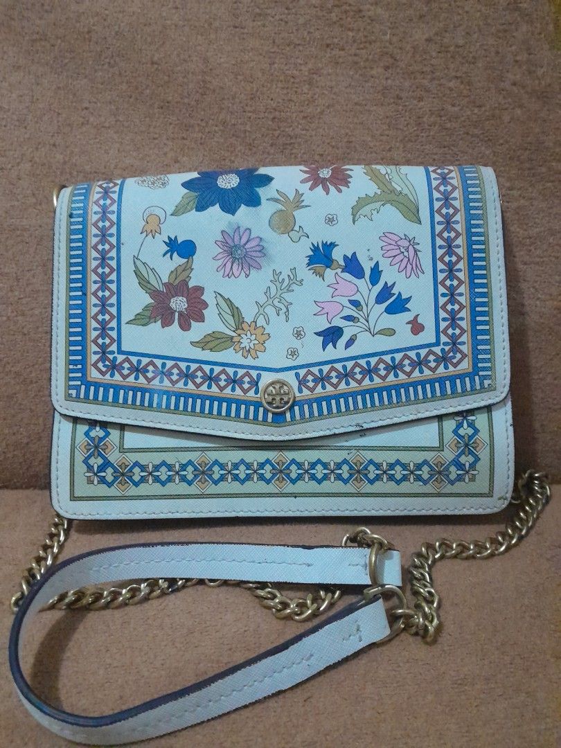 Tory Burch Floral Chain Sling Wallet (Category: Luxury Bags & Wallets) located in Quezon City. Submitted by lalaine.r (Listing ID 1418168638, Image 1). Description: Tory Burch chain wallet features a beautiful floral design. It has a chain and leather strap and a magnetic snap closure. The exterior has colorful floral patterns and a decorative border. The Tory Burch logo is visible on the front. Issues: - fading at the back part of the bag - need