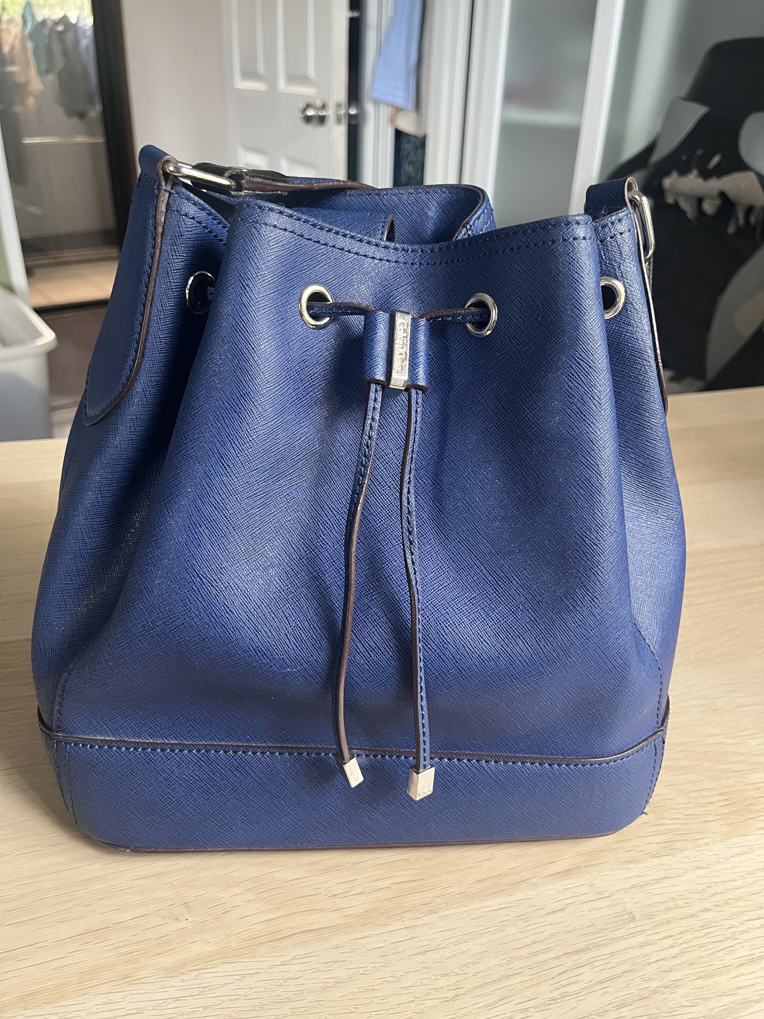 Calvin Klein Bucket Bag - Navy Blue (Category: Luxury Bags & Wallets) located in Manila. Submitted by alexashops (Listing ID 1418268401, Image 1). Description: - Calvin Klein bucket bag - Navy blue color - Bought in US - Drawstring closure - Shoulder strap - Silver-tone hardware - Calvin Klein logo on front - Textured material - Structured shape - Flat base.