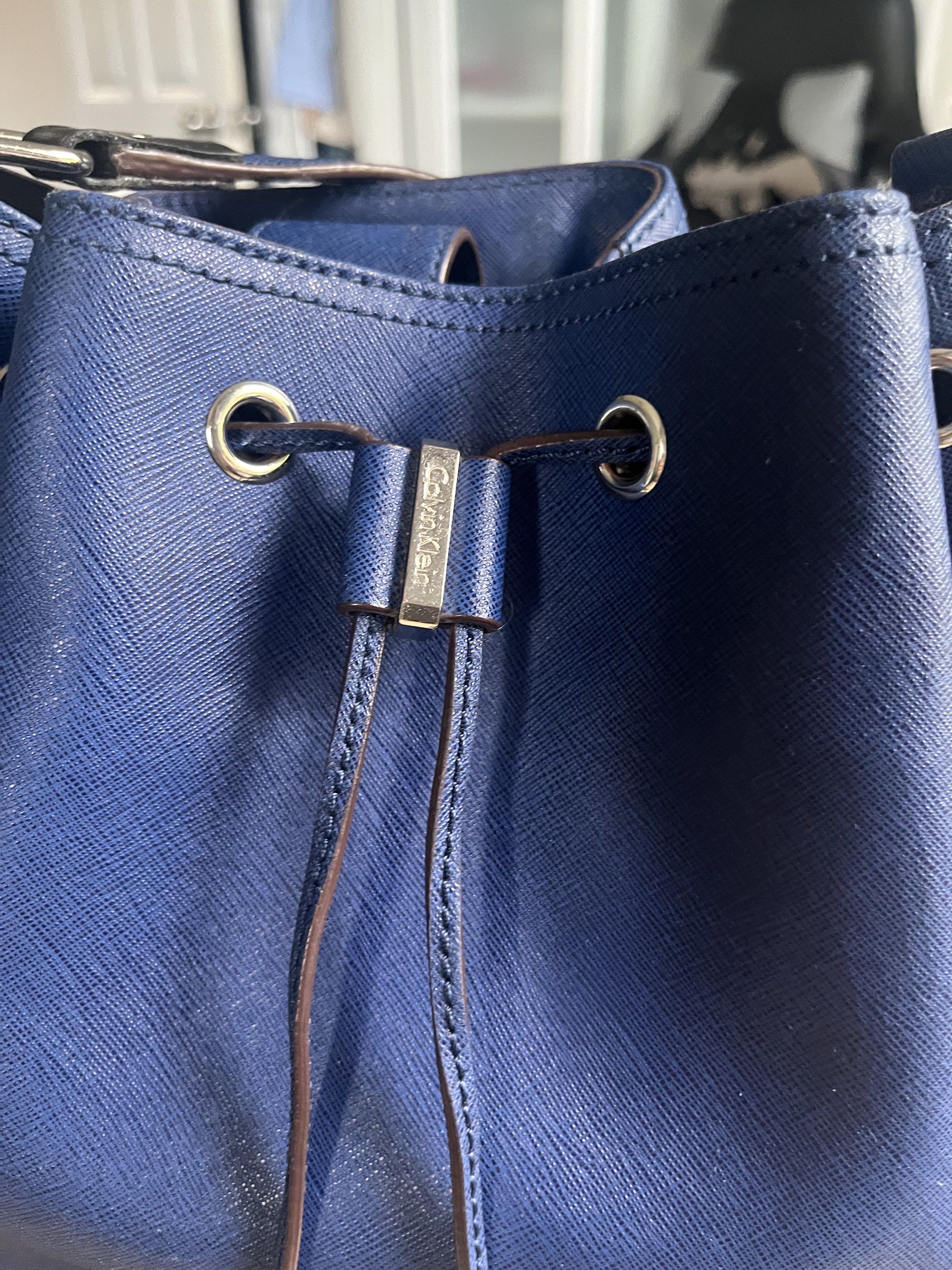 Calvin Klein Bucket Bag - Navy Blue (Category: Luxury Bags & Wallets) located in Manila. Submitted by alexashops (Listing ID 1418268401, Image 3). Description: - Calvin Klein bucket bag - Navy blue color - Bought in US - Drawstring closure - Shoulder strap - Silver-tone hardware - Calvin Klein logo on front - Textured material - Structured shape - Flat base.