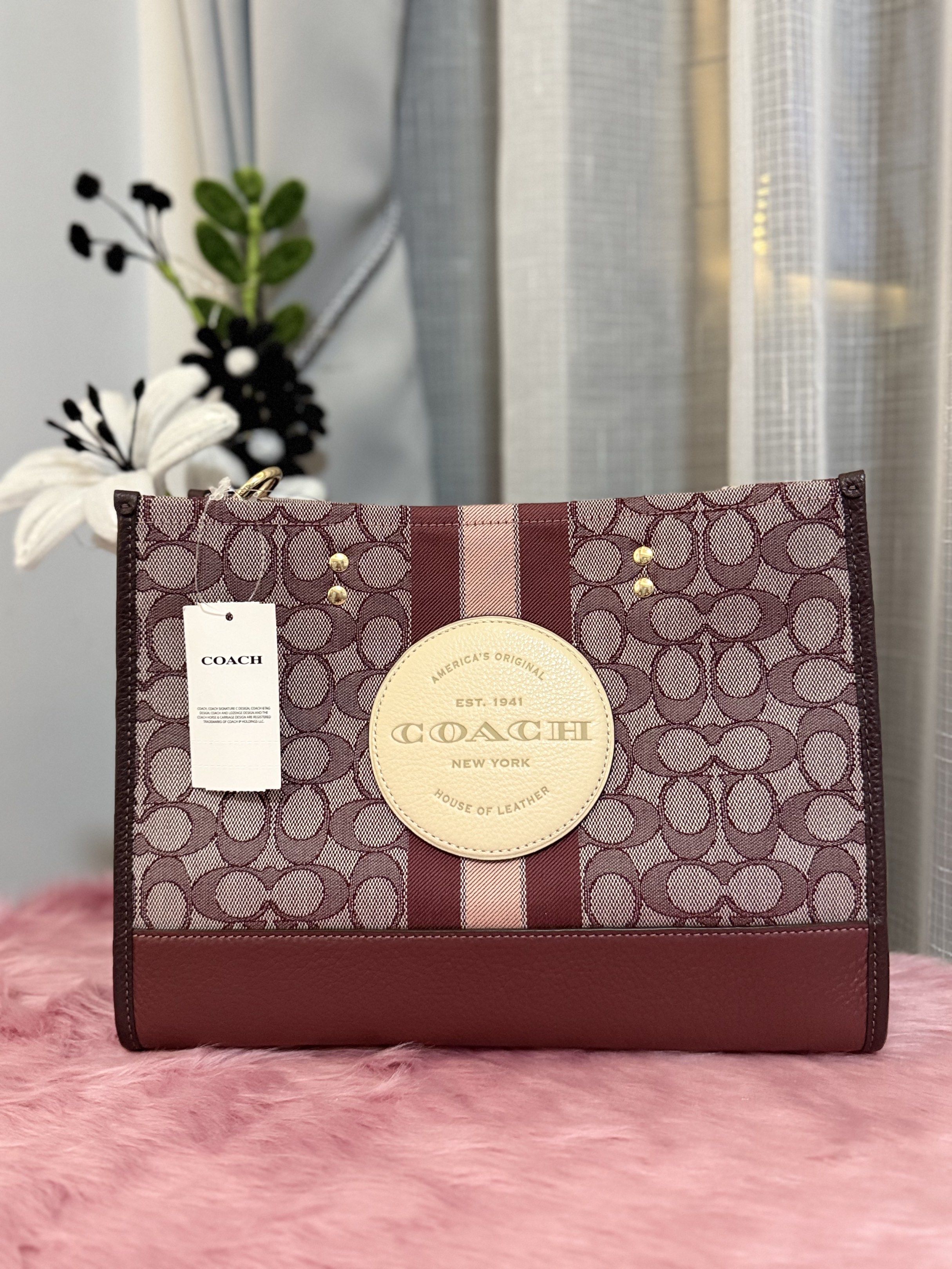 Coach Tote Bag (Category: Luxury Bags & Wallets) located in Padre Garcia. Submitted by riailagan49560 (Listing ID 1418334569, Image 1). Description: - Coach tote bag - Signature pattern - Burgundy base - Central stripe design - Includes Coach tag - Features Coach logo.