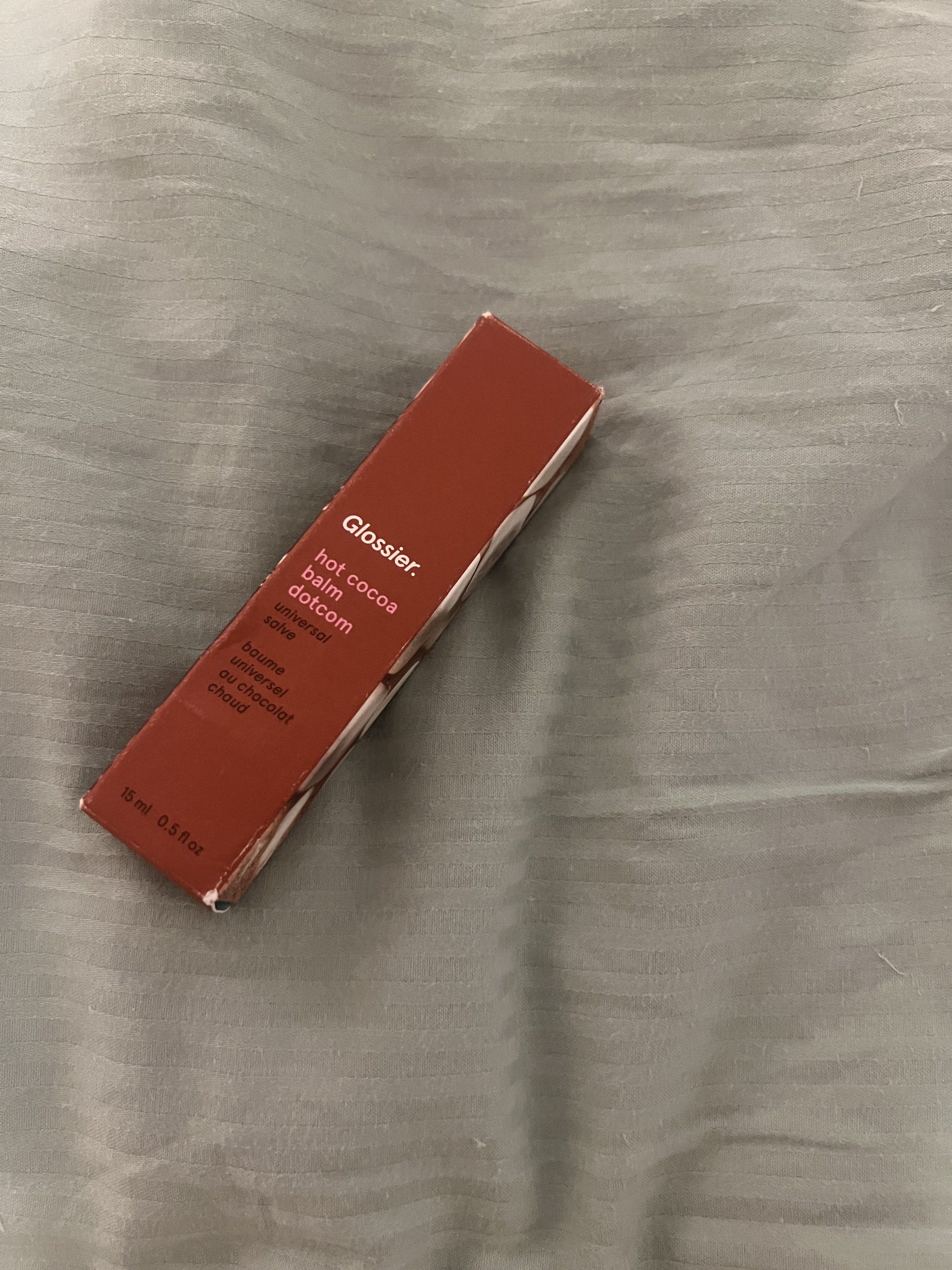 Glossier Hot Cocoa Balm Dotcom (Category: Makeup) located in Taguig. Submitted by new_again_ (Listing ID 1418324867, Image 3). Description: - Glossier Hot Cocoa Balm Dotcom - Scent: Hot Cocoa - Size: 15 ml / 0.5 fl oz - Packaging: Brown box with marshmallow design.