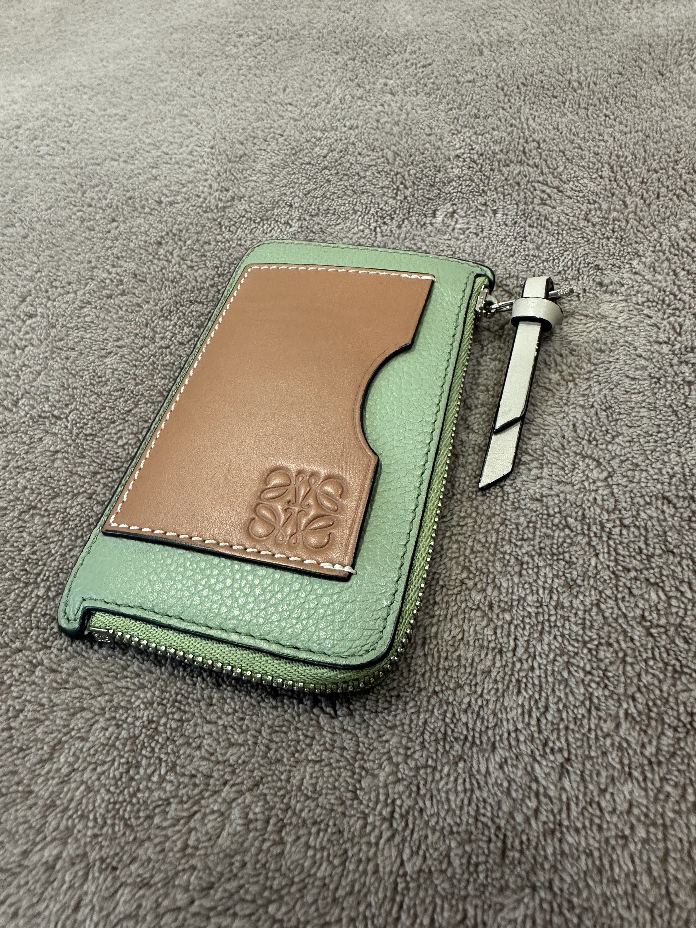 Loewe Cardholder Wallet (Category: Luxury Bags & Wallets) located in Bacolod City. Submitted by katayellow (Listing ID 1418401161, Image 1). Description: - Loewe cardholder wallet - Color: Mint green and brown - Zip closure - Multiple card slots - Loewe logo on front - Light beige interior - Includes wrist strap.