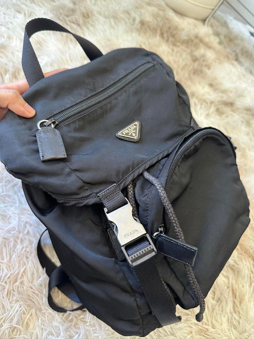 Prada Black Nylon Backpack (Category: Luxury Bags & Wallets) located in Taguig. Submitted by luxuryfindsforless (Listing ID 1418332649, Image 3). Description: - Prada nylon backpack - Front pocket - Drawstring closure - Adjustable shoulder straps - Top handle - Prada logo on front - Prada Milano interior label - Approximately 12 inches height.