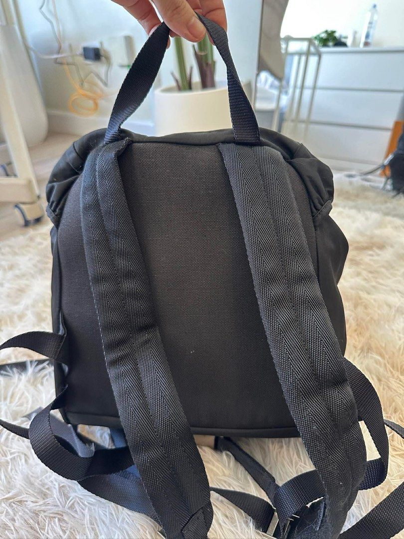 Prada Black Nylon Backpack (Category: Luxury Bags & Wallets) located in Taguig. Submitted by luxuryfindsforless (Listing ID 1418332649, Image 2). Description: - Prada nylon backpack - Front pocket - Drawstring closure - Adjustable shoulder straps - Top handle - Prada logo on front - Prada Milano interior label - Approximately 12 inches height.